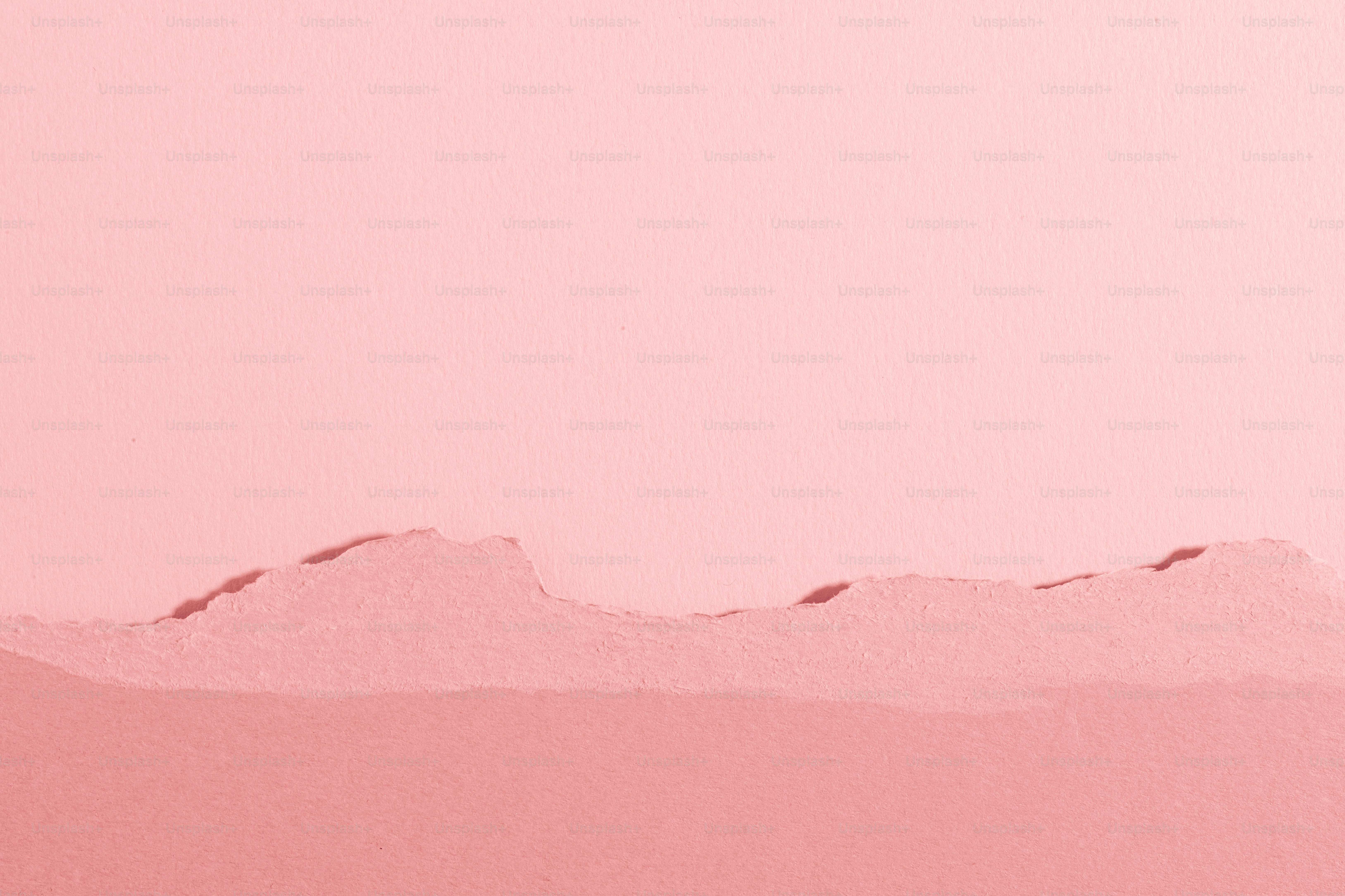 A bird flying over a pink mountain range