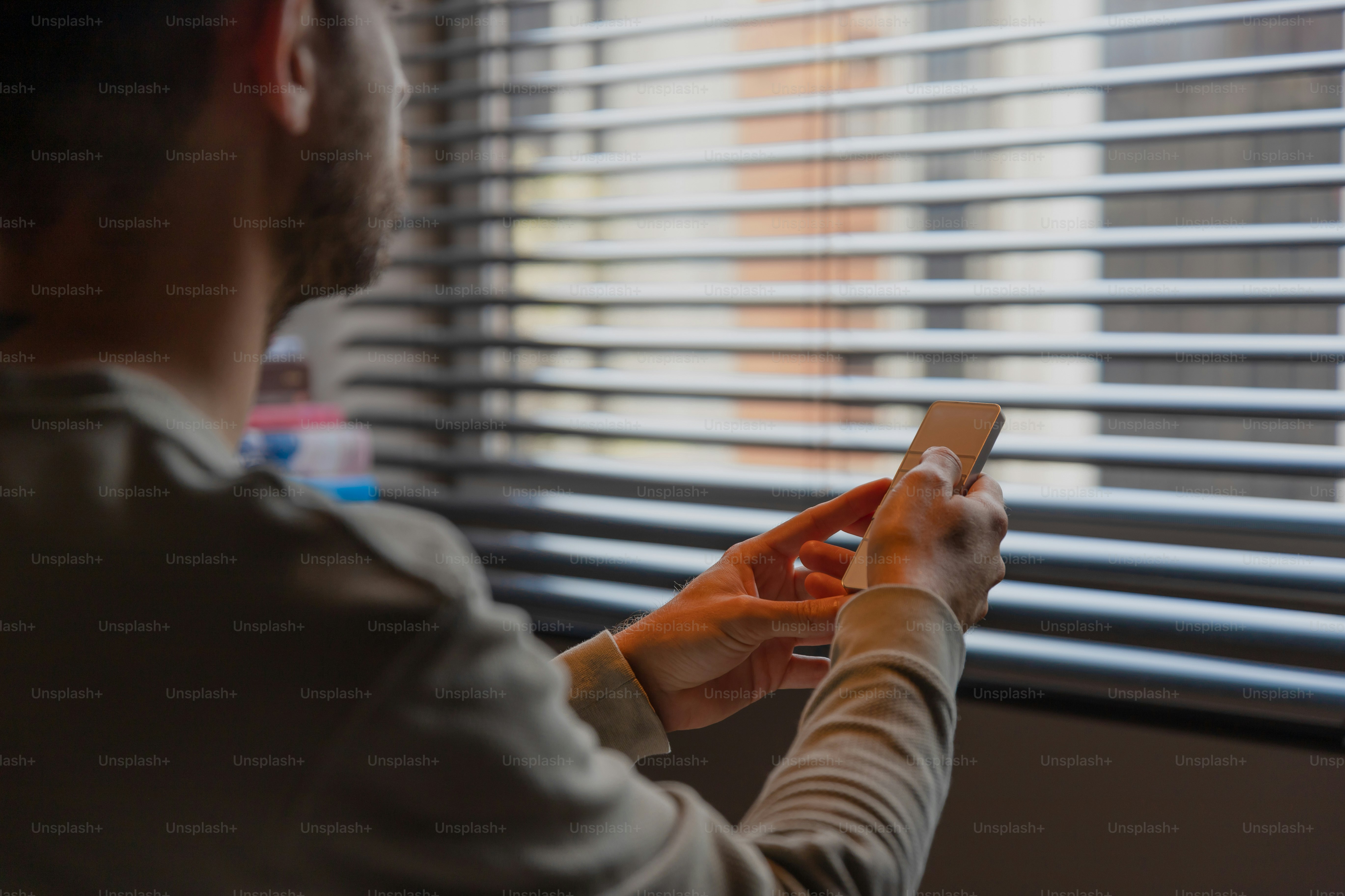 A woman looking out a window with a cell phone photo – Smart technology ...