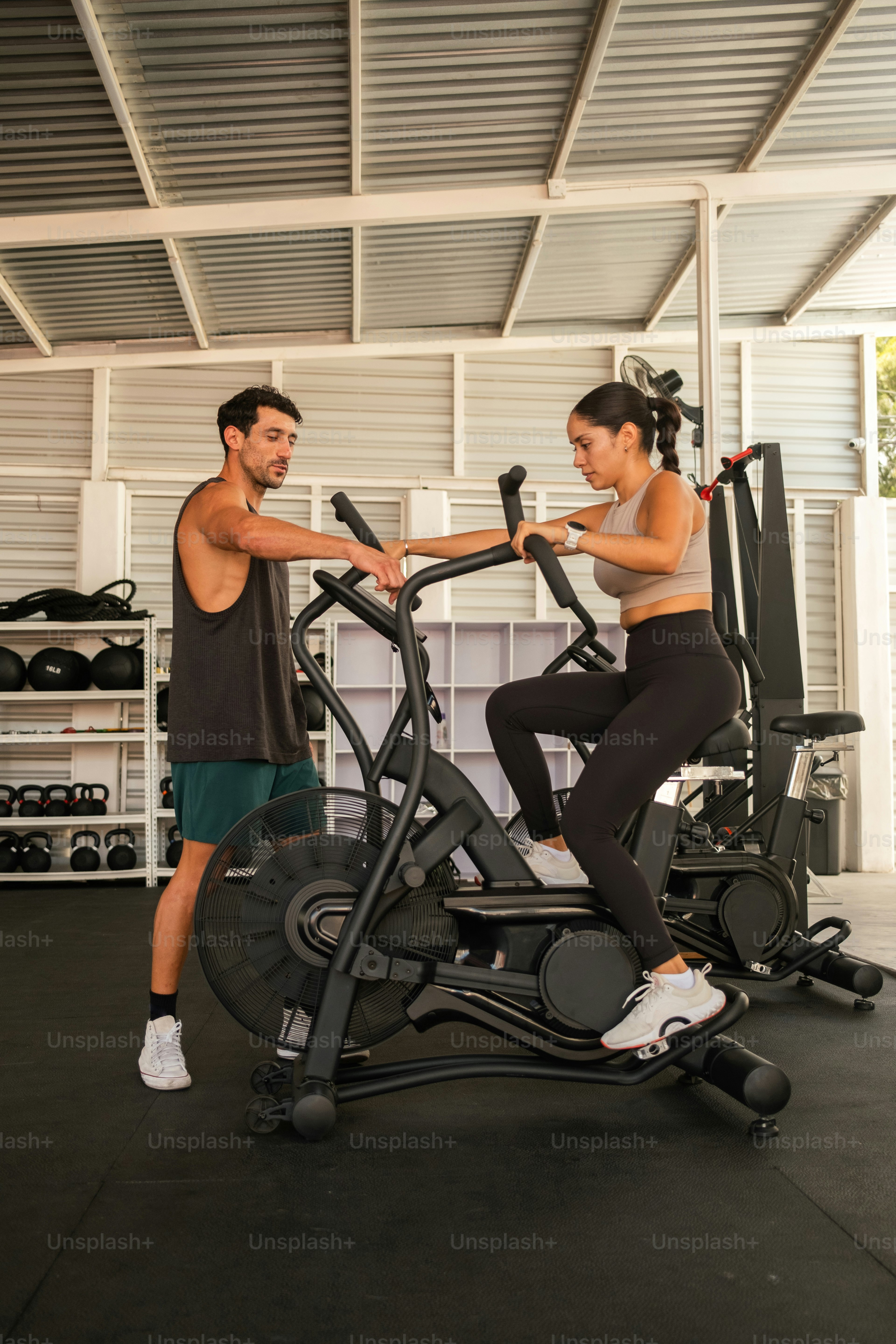 Un hombre y una mujer en un gimnasio en bicicletas estáticas