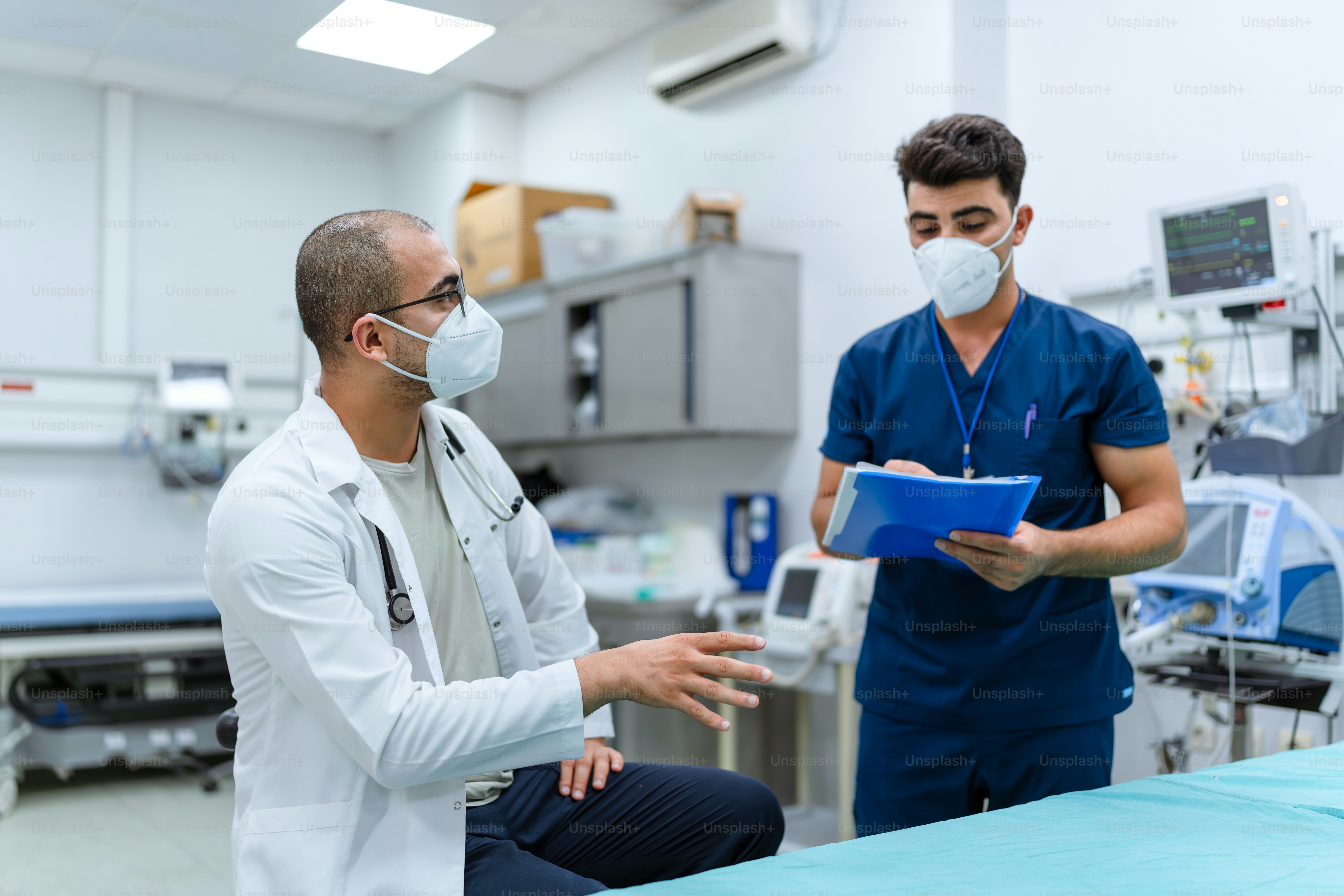 A man in a white lab coat and a man in a blue scrub suit are
