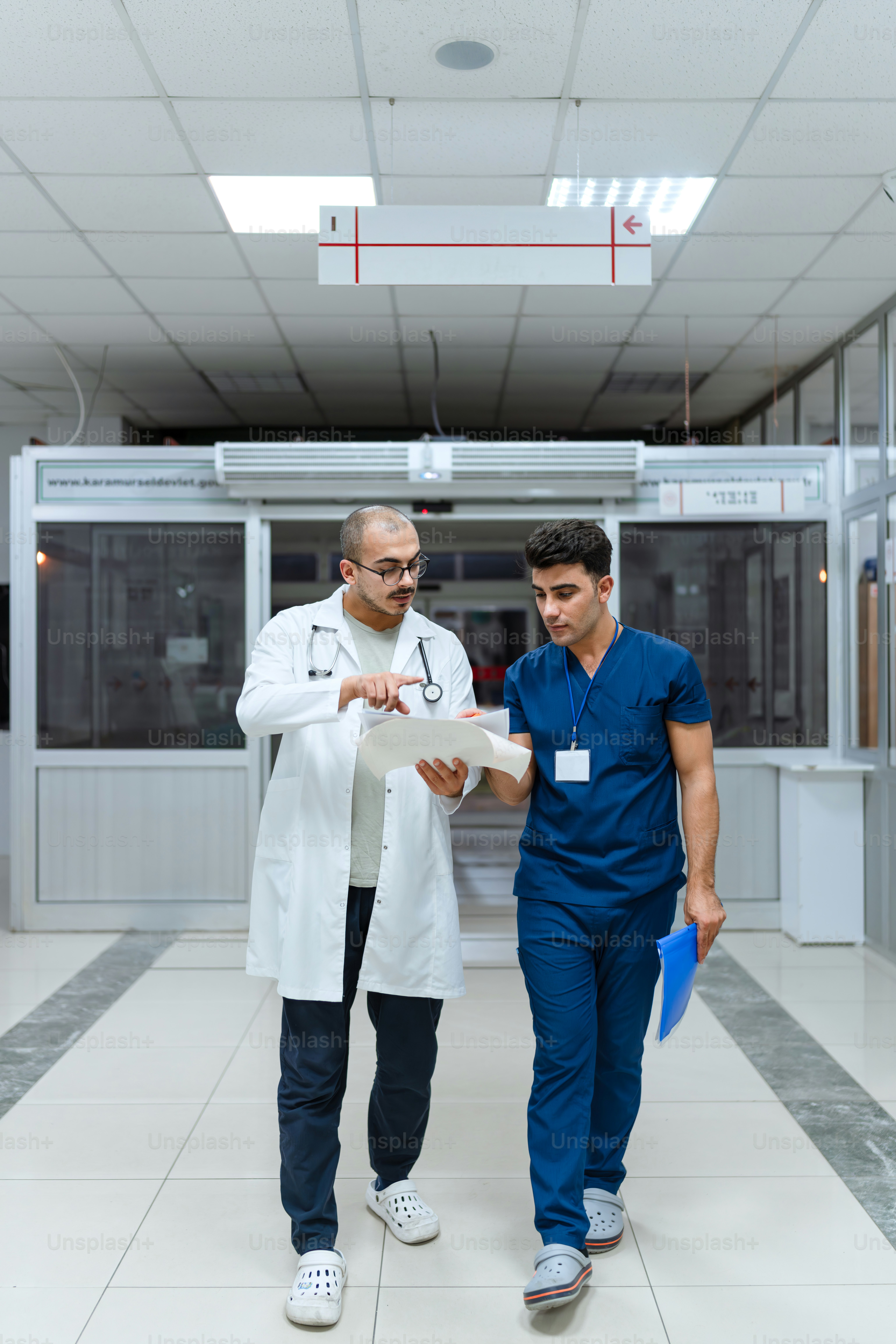 Two men in scrubs walking down a hospital hallway