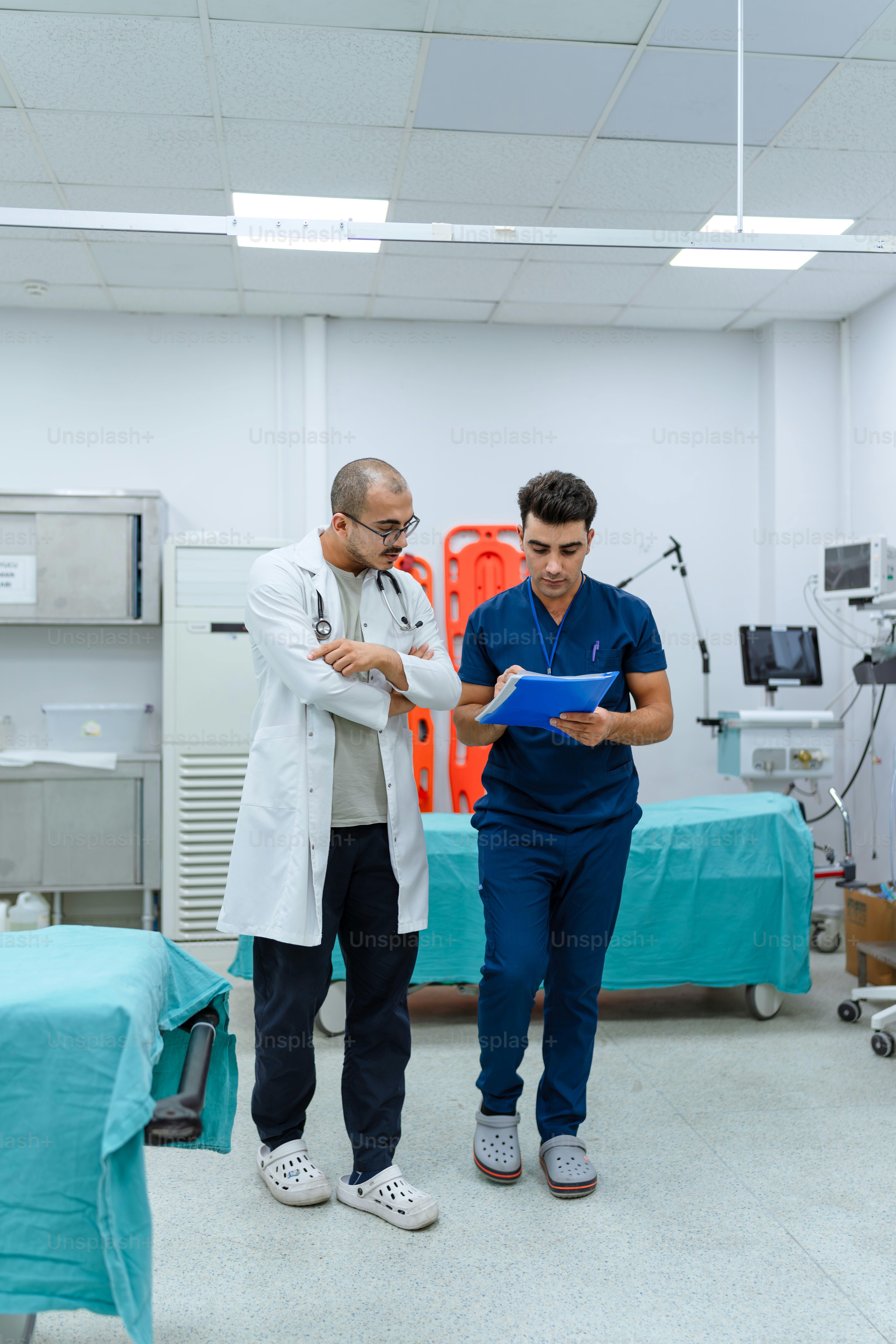 Two men in a hospital room looking at a clipboard