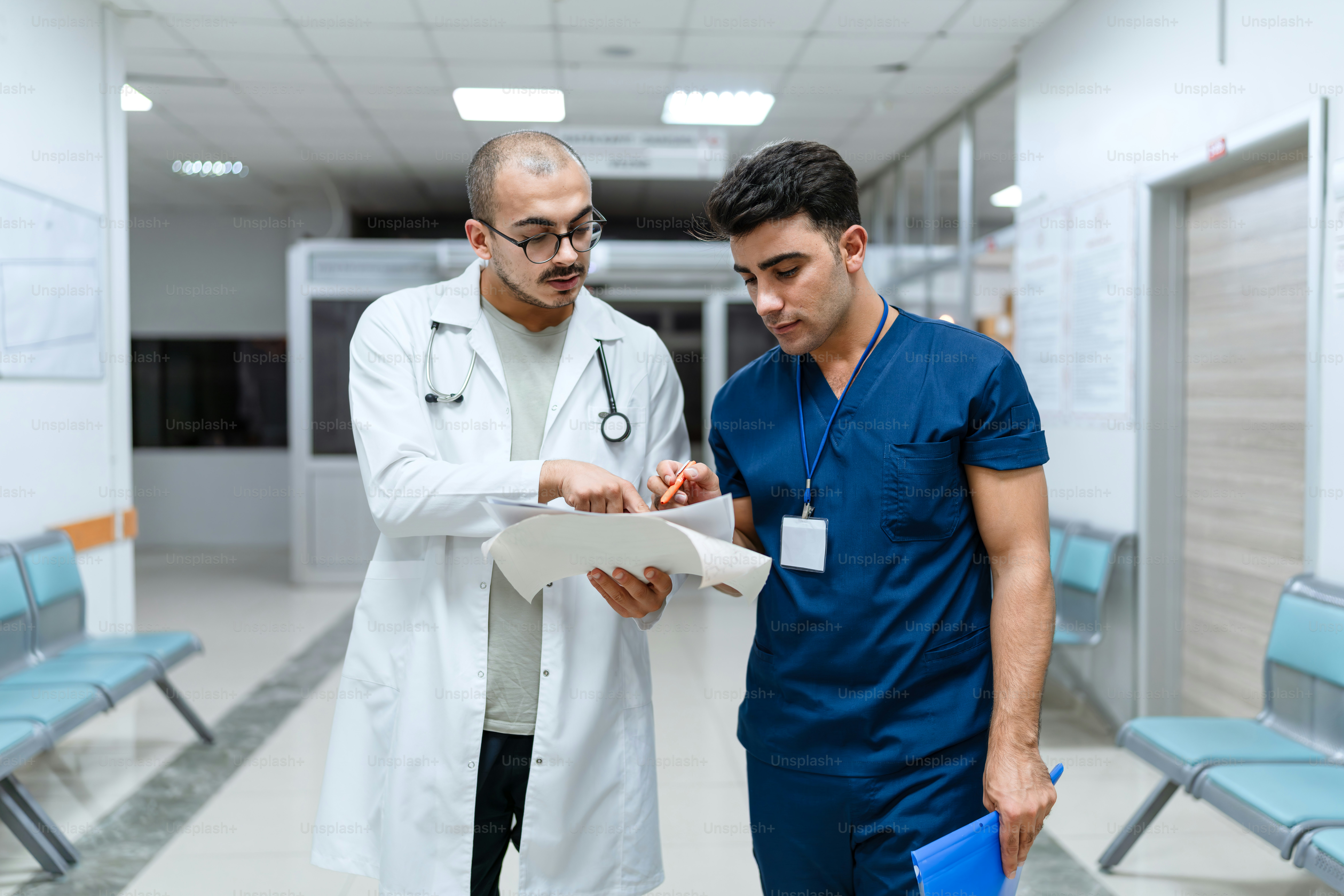 Zwei Ärzte schauen auf ein Klemmbrett in einem Krankenhaus