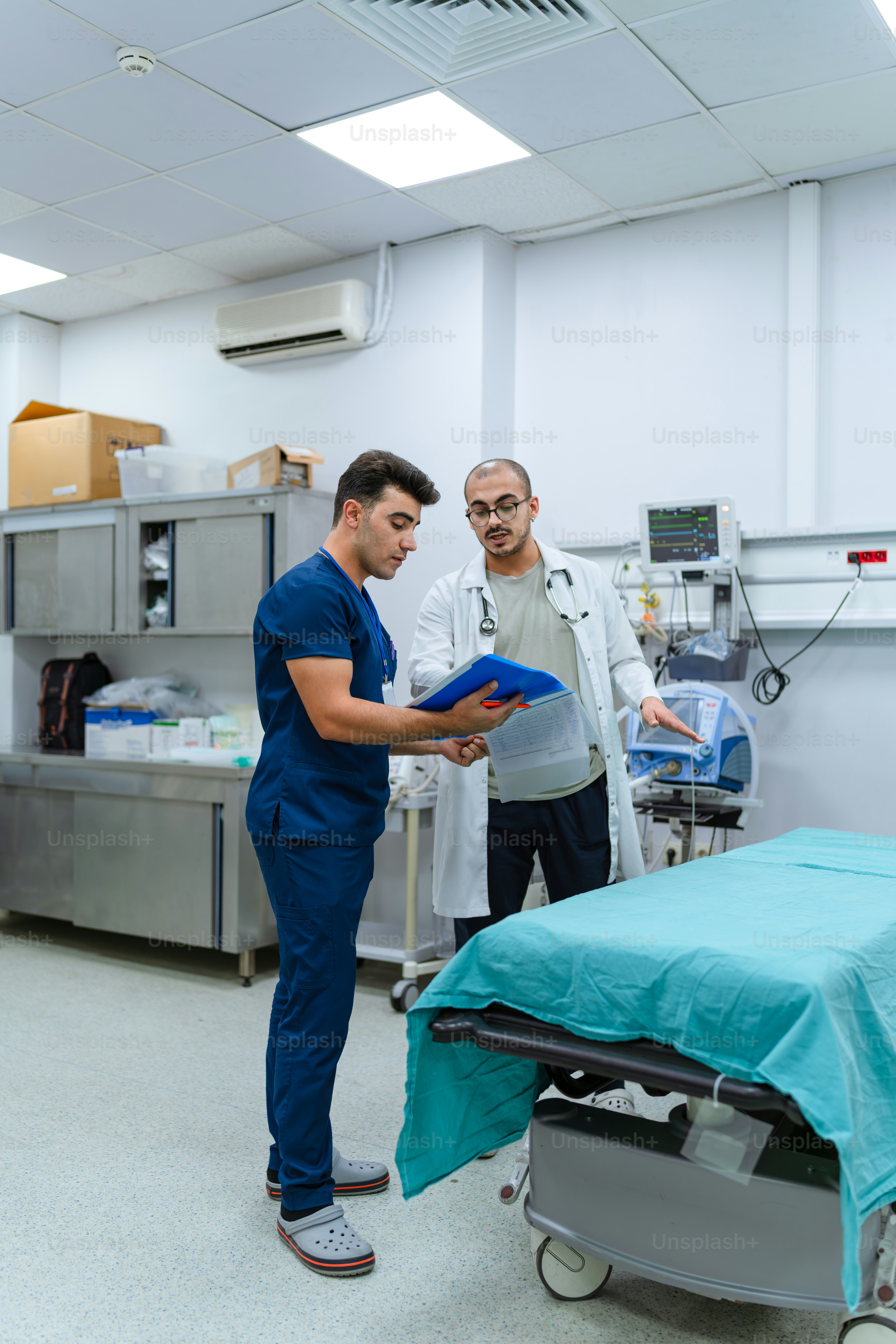 A couple of men standing around a hospital room