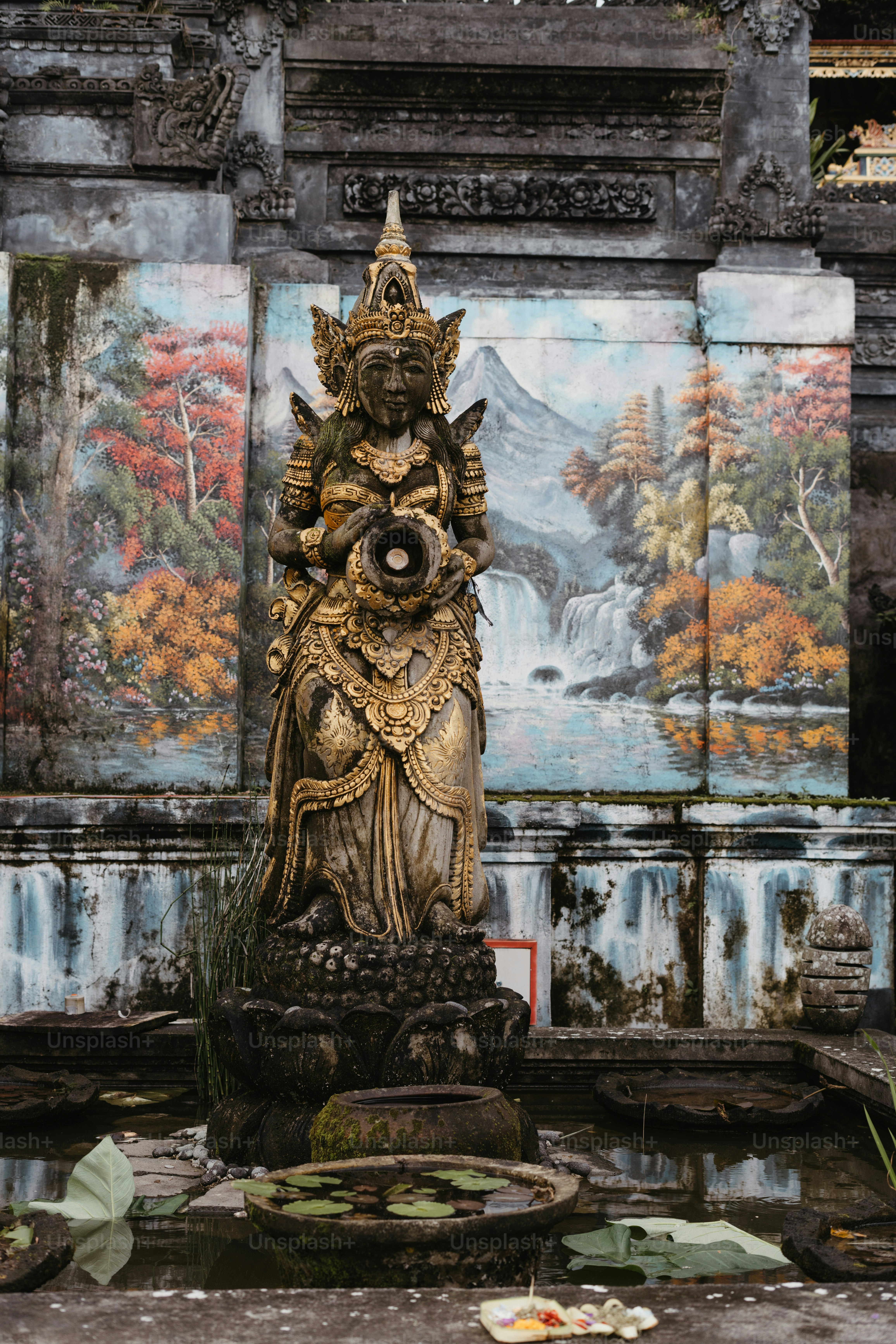 A statue in front of a wall with paintings on it