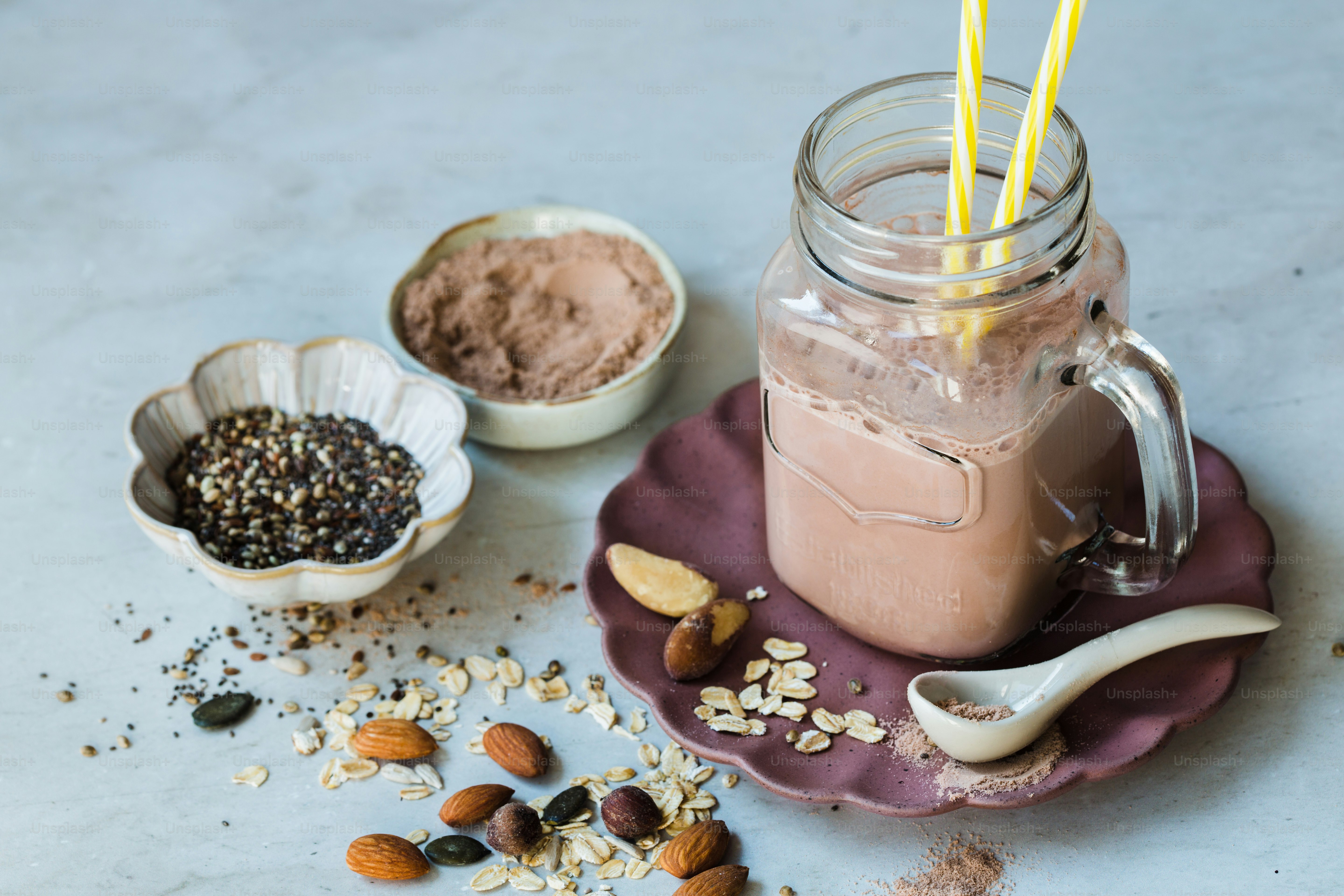 A smoothie in a mason jar surrounded by nuts and other ingredients