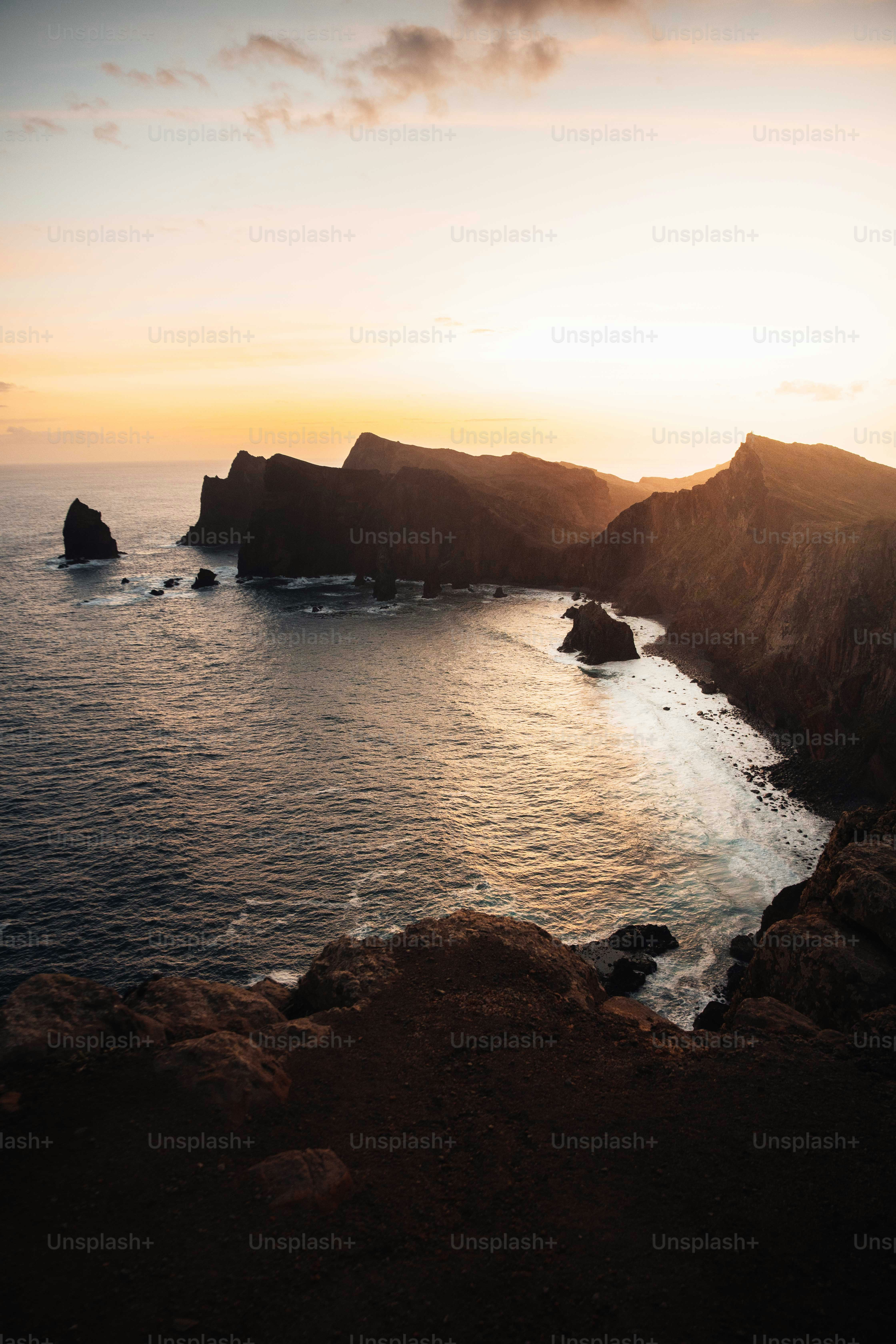 The sun is setting over a rocky coastline photo – Blue Image on Unsplash