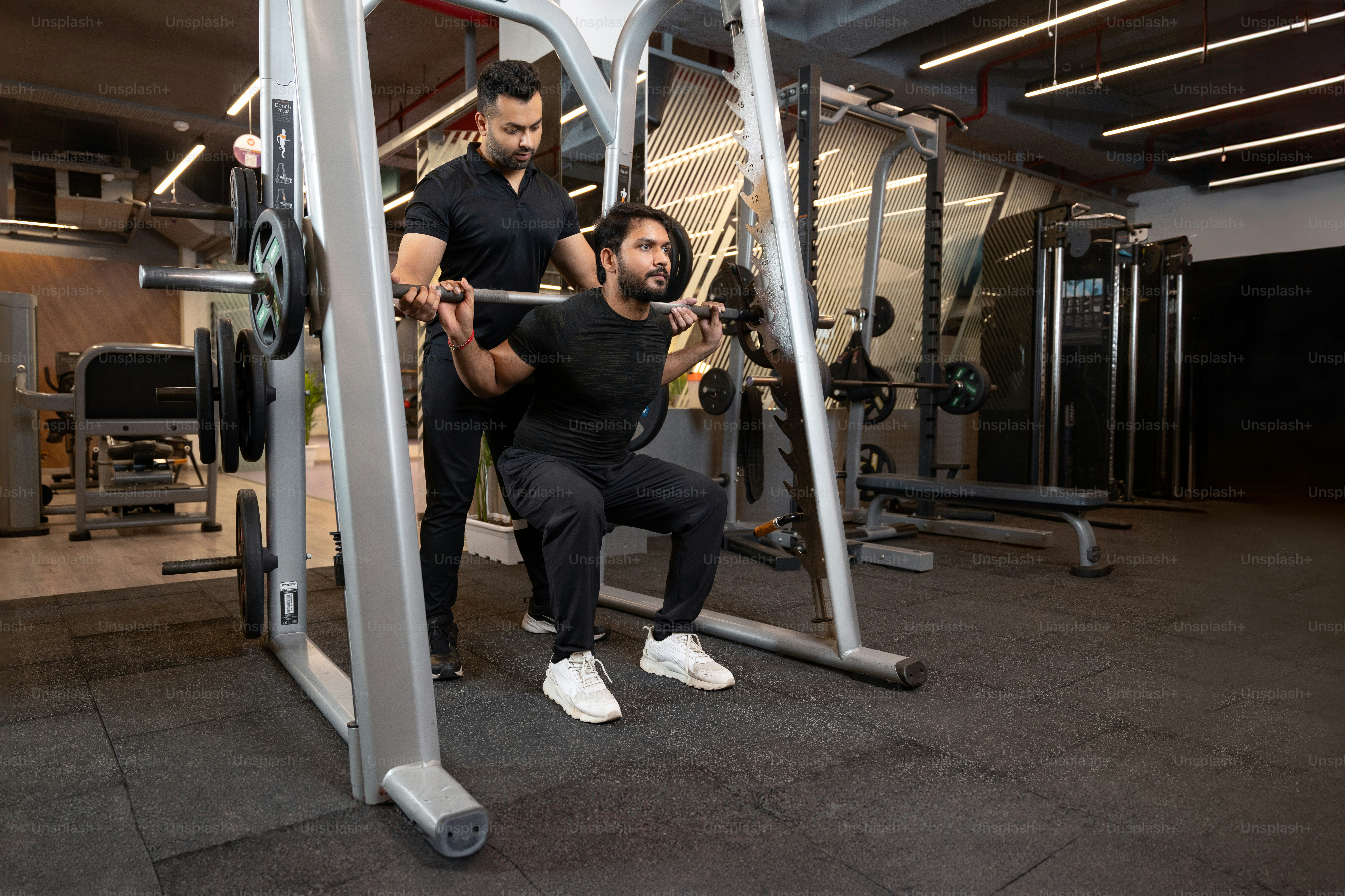 A man squats on a machine in a gym