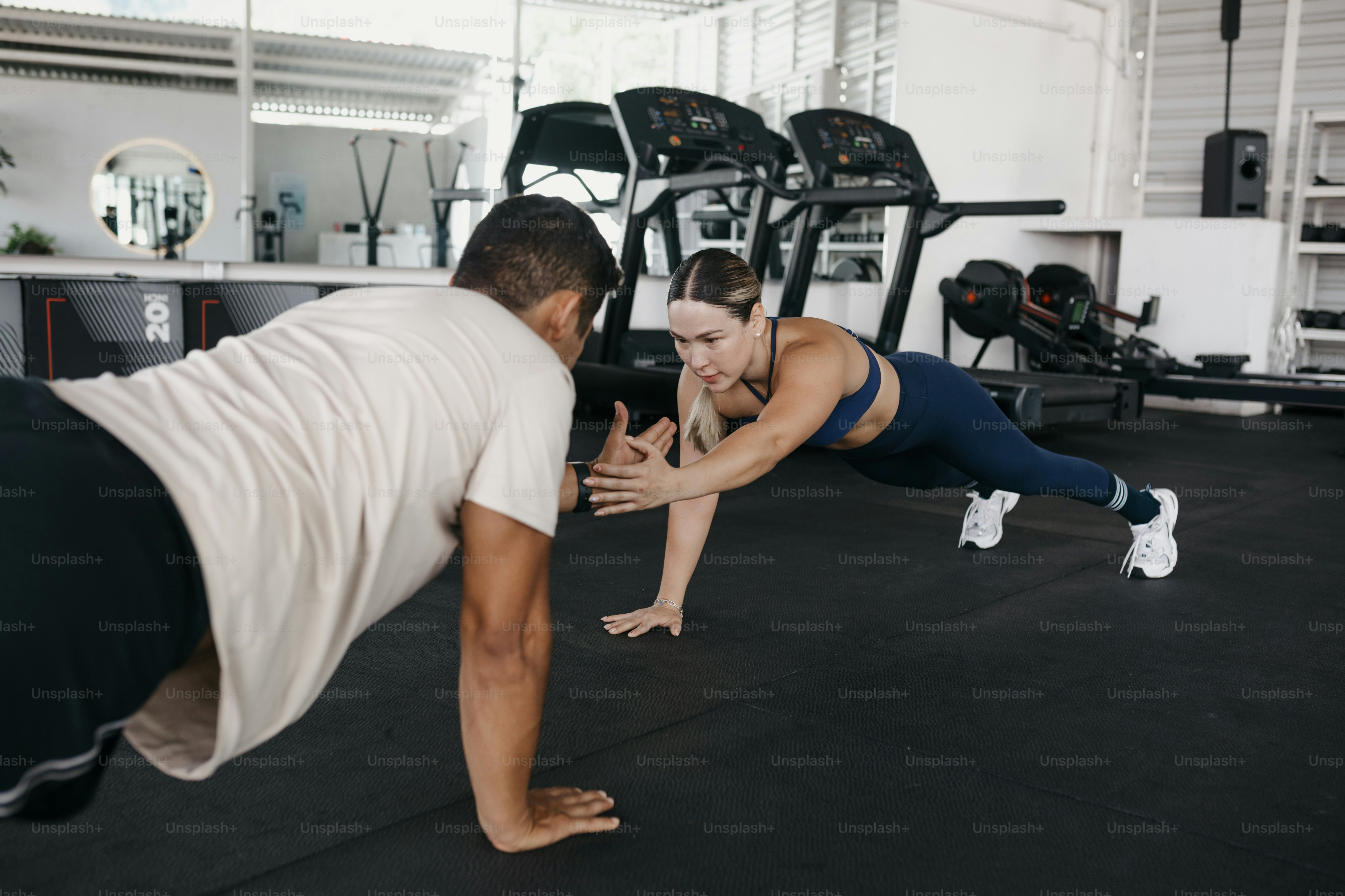 Ein Mann und eine Frau machen Liegestütze in einem Fitnessstudio