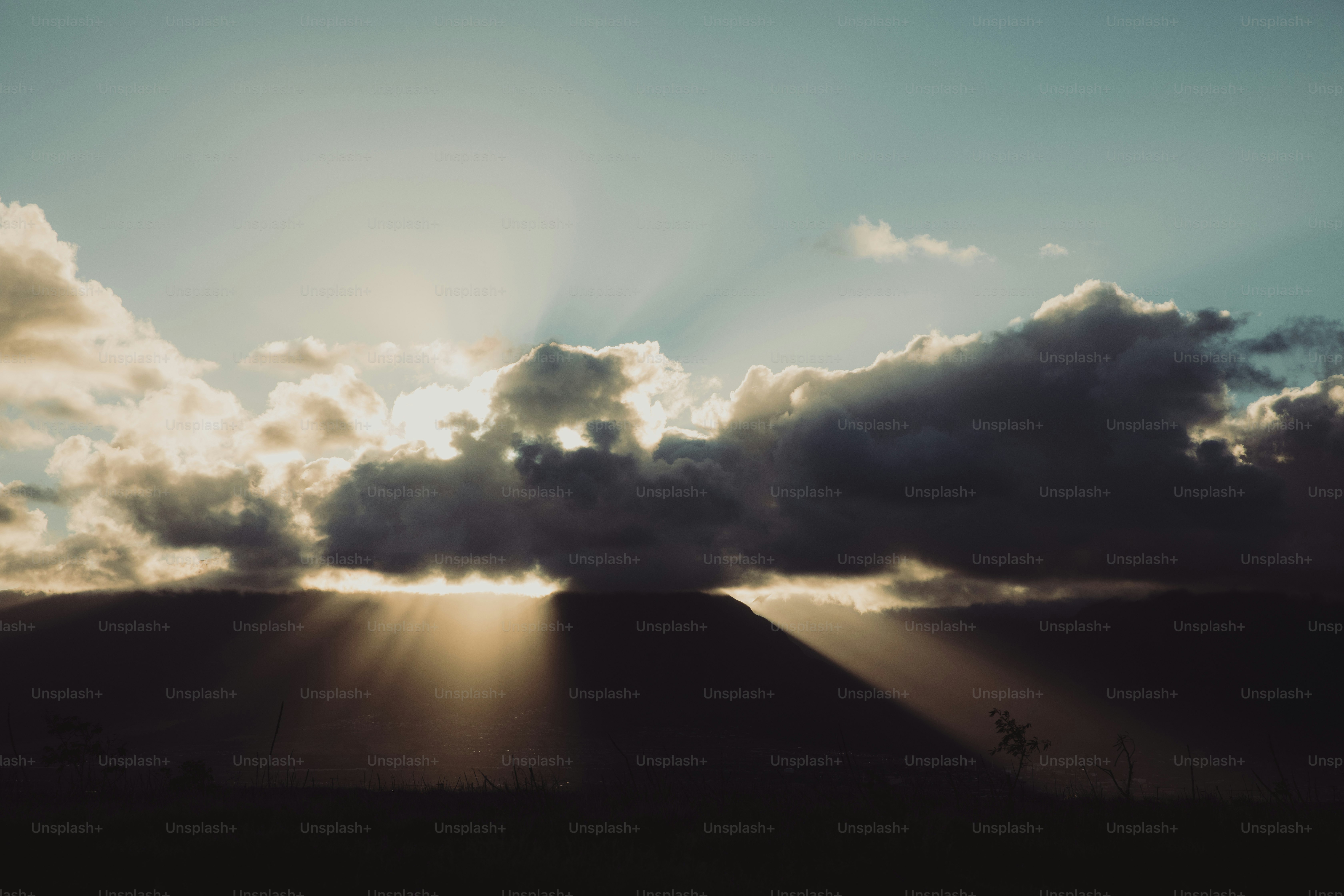The sun is shining through the clouds over a field