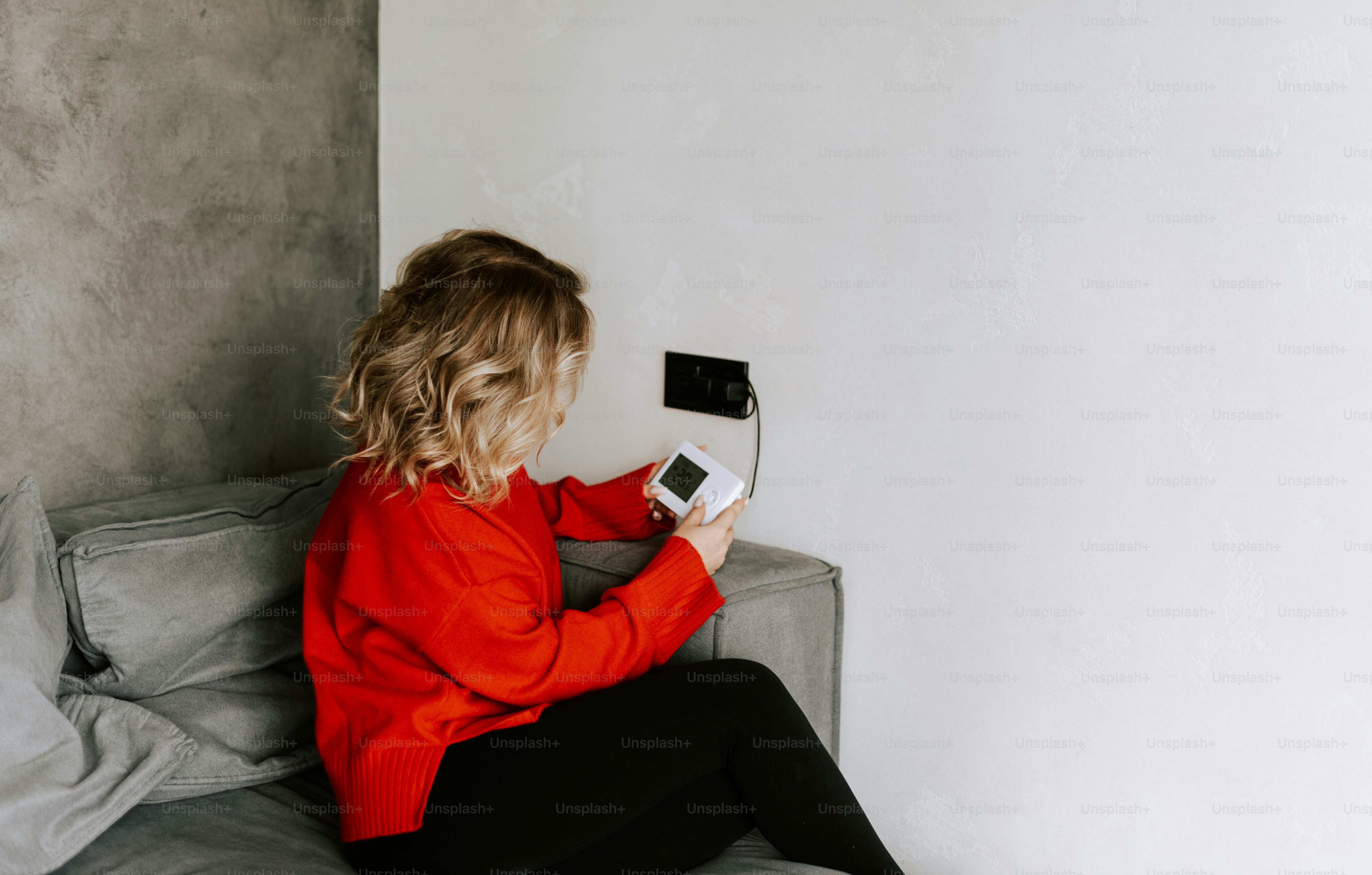 Una mujer sentada en un sofá sosteniendo un control remoto