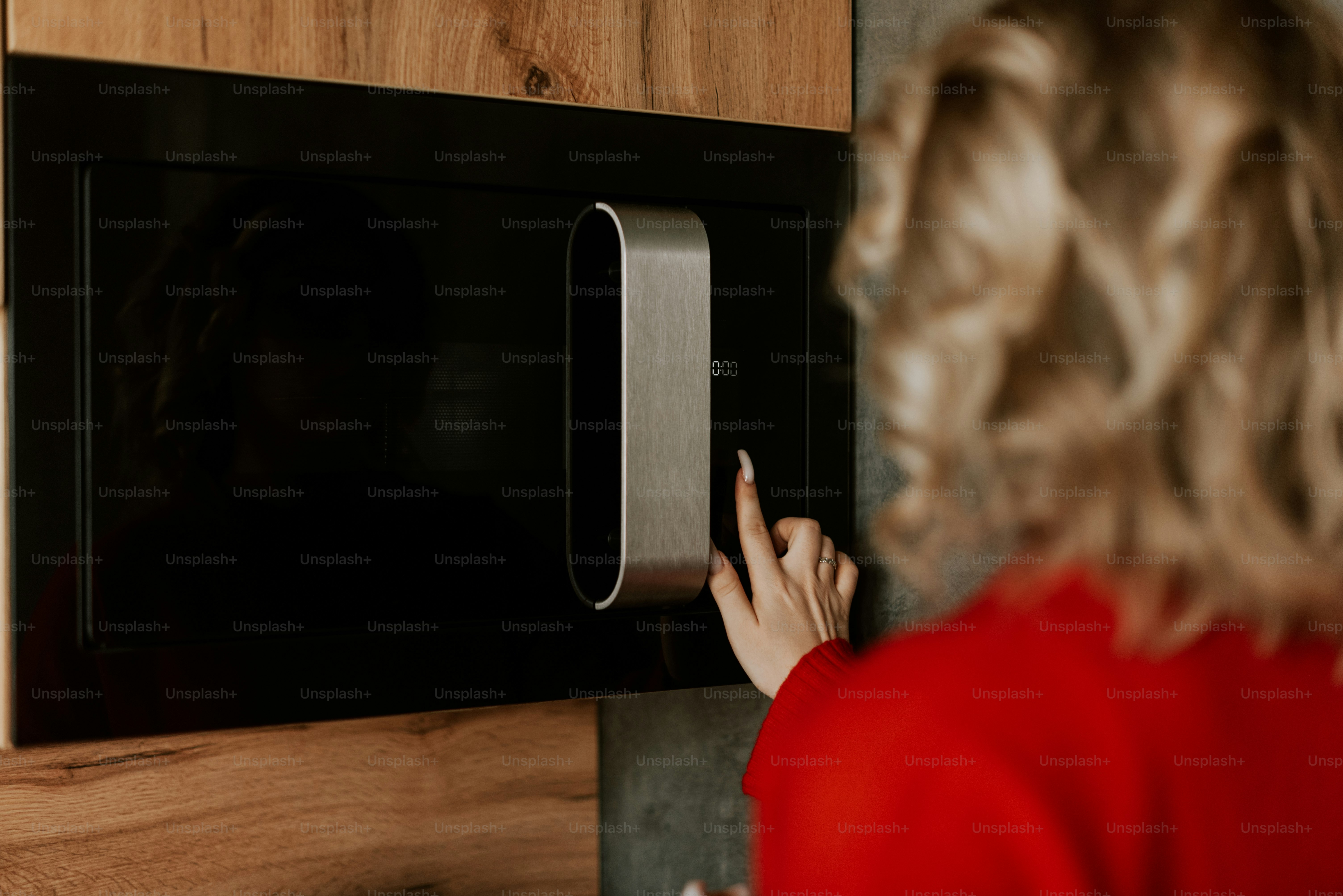 Una mujer con una camisa roja está usando un microondas