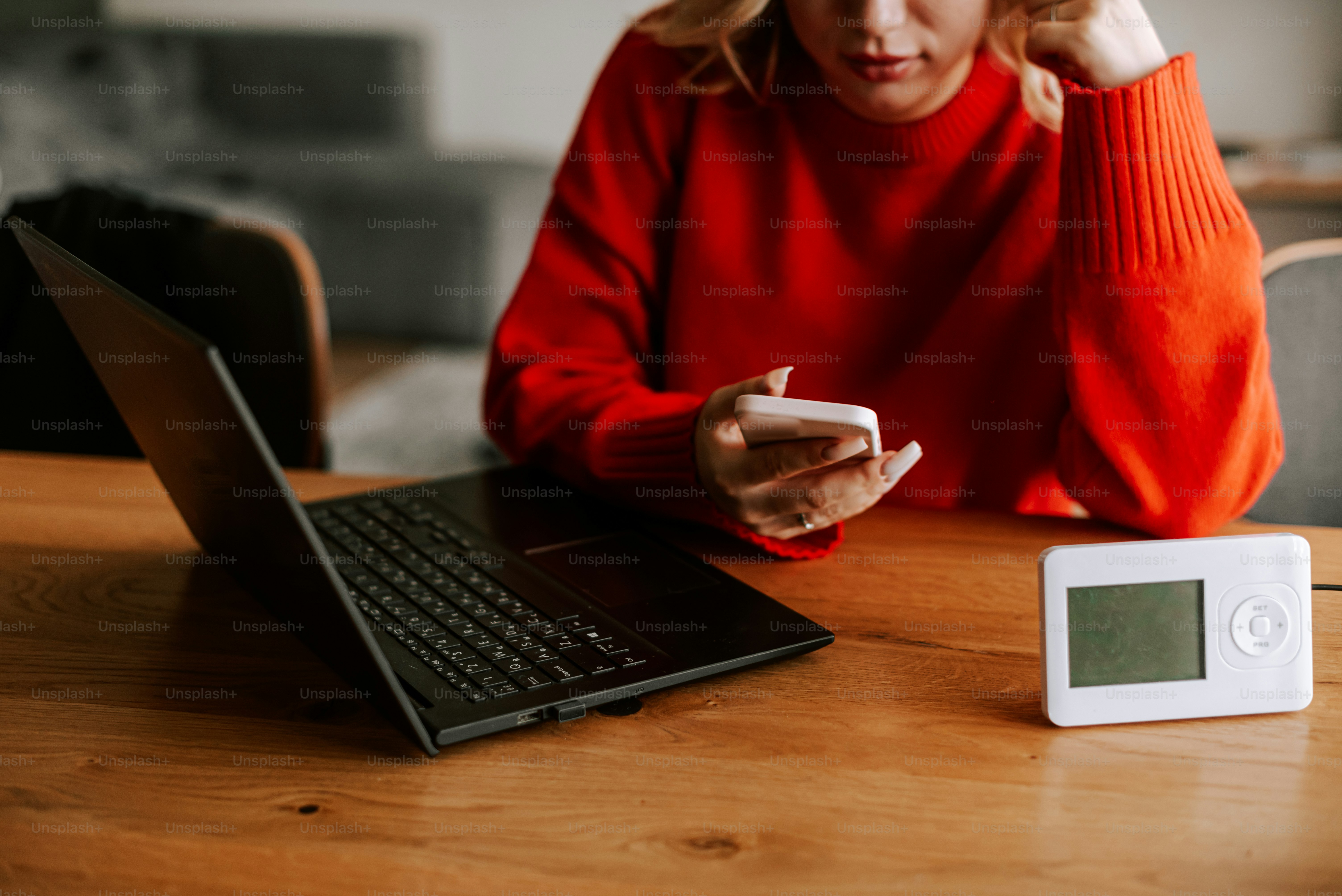 Una mujer sentada en una mesa mirando su teléfono móvil