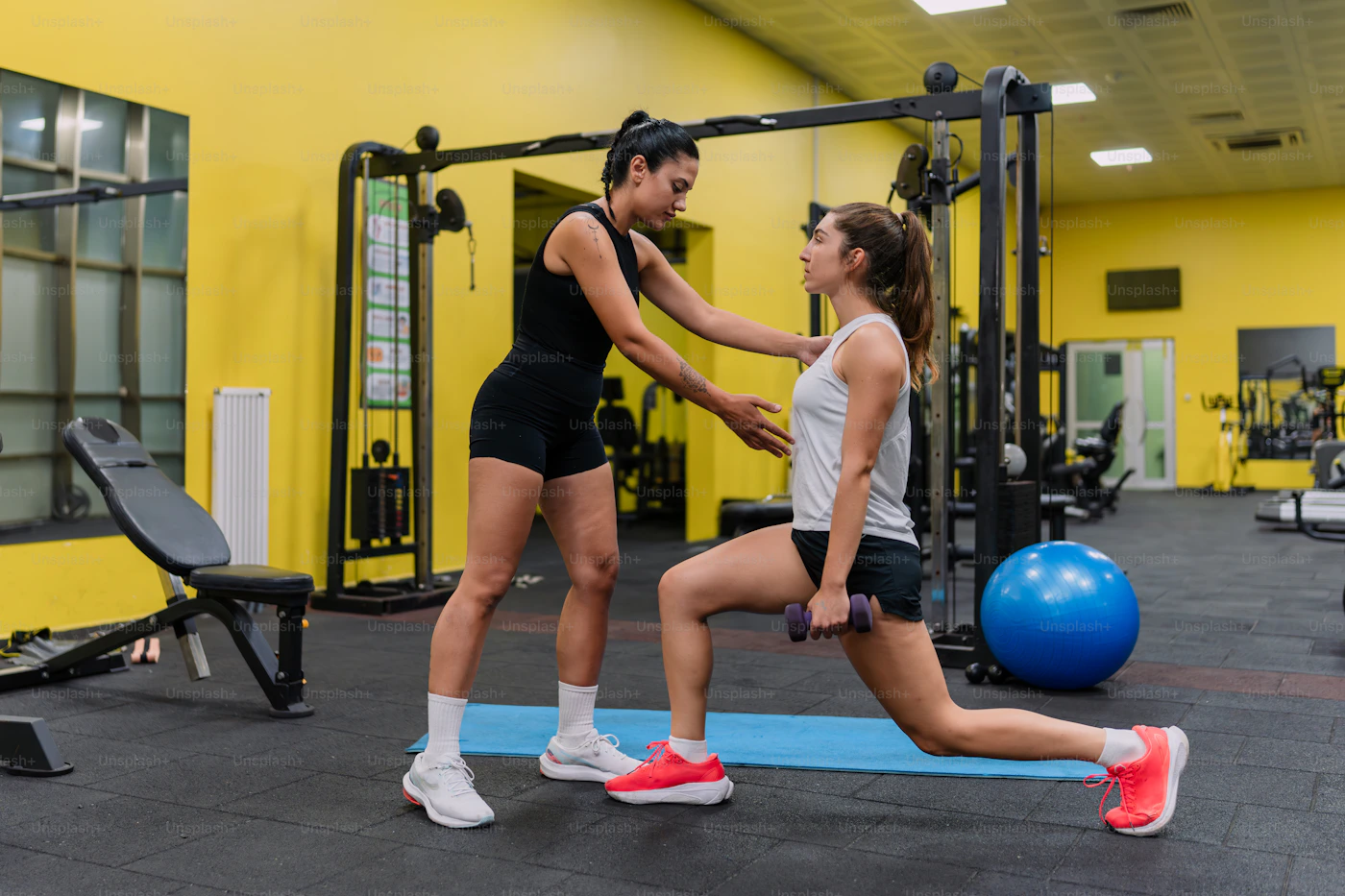 Treinadora acompanhando aluna durante exercício