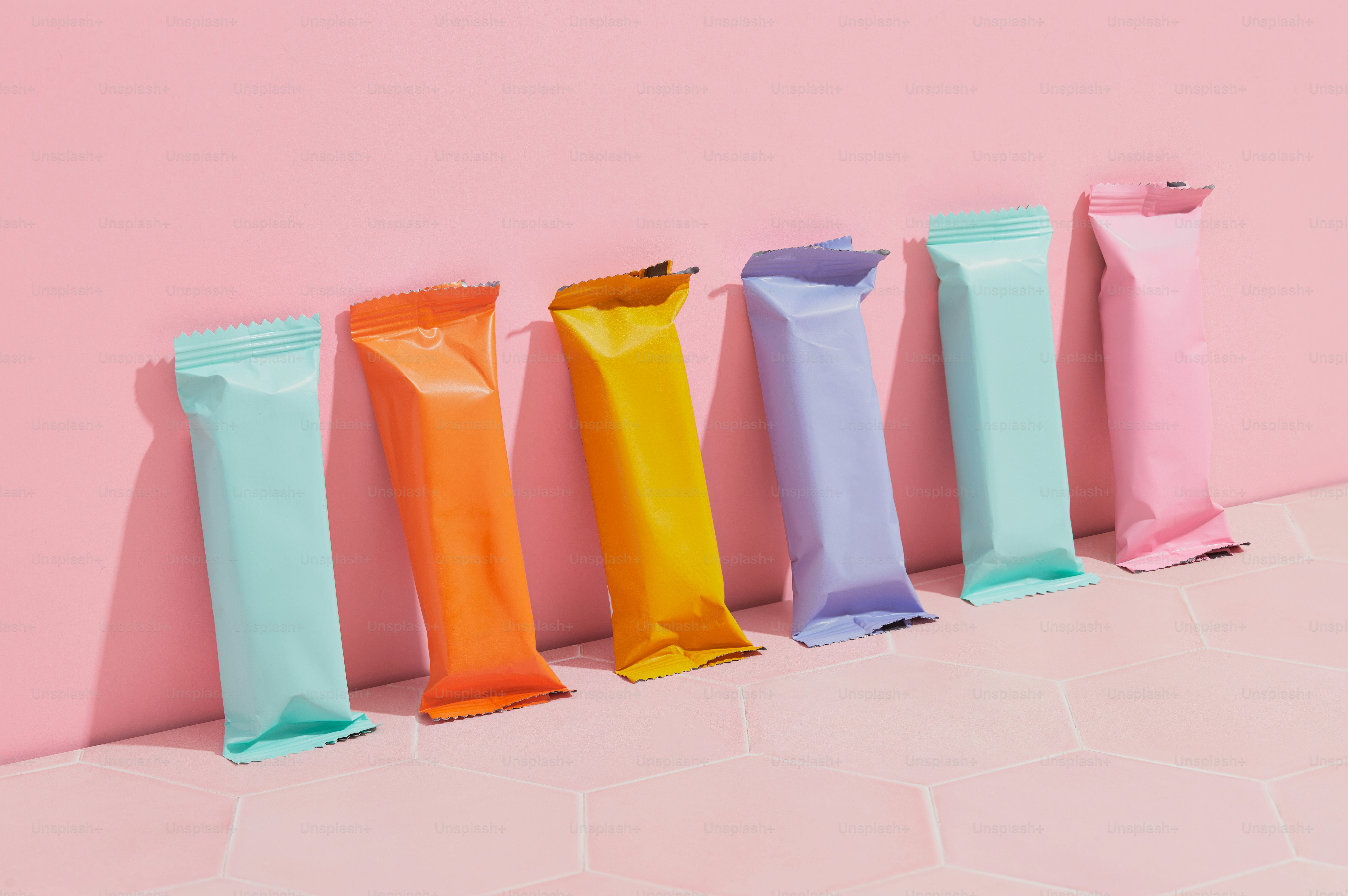 A row of candy bars lined up against a pink wall