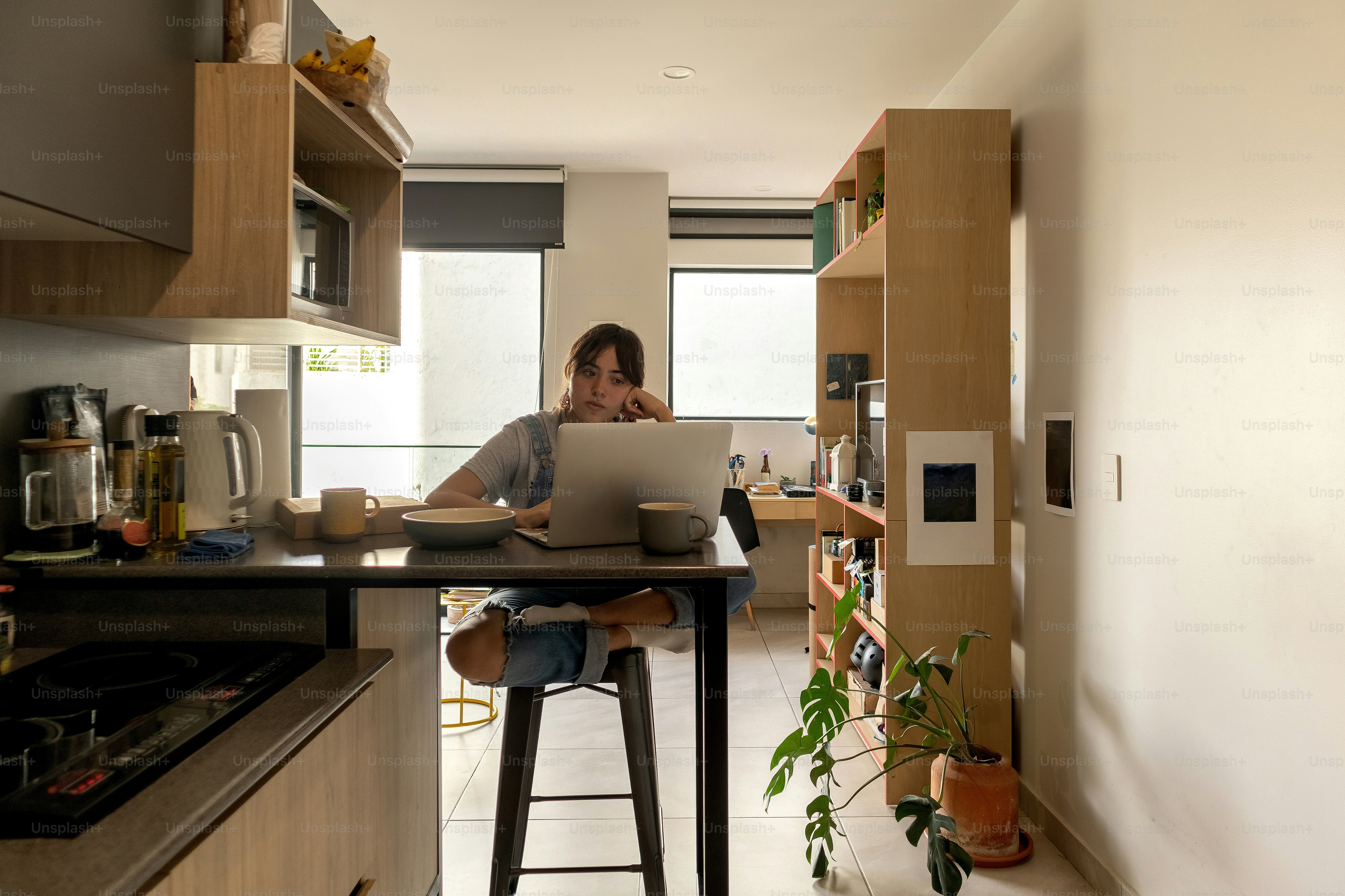 A man sitting at a kitchen counter using a laptop computer