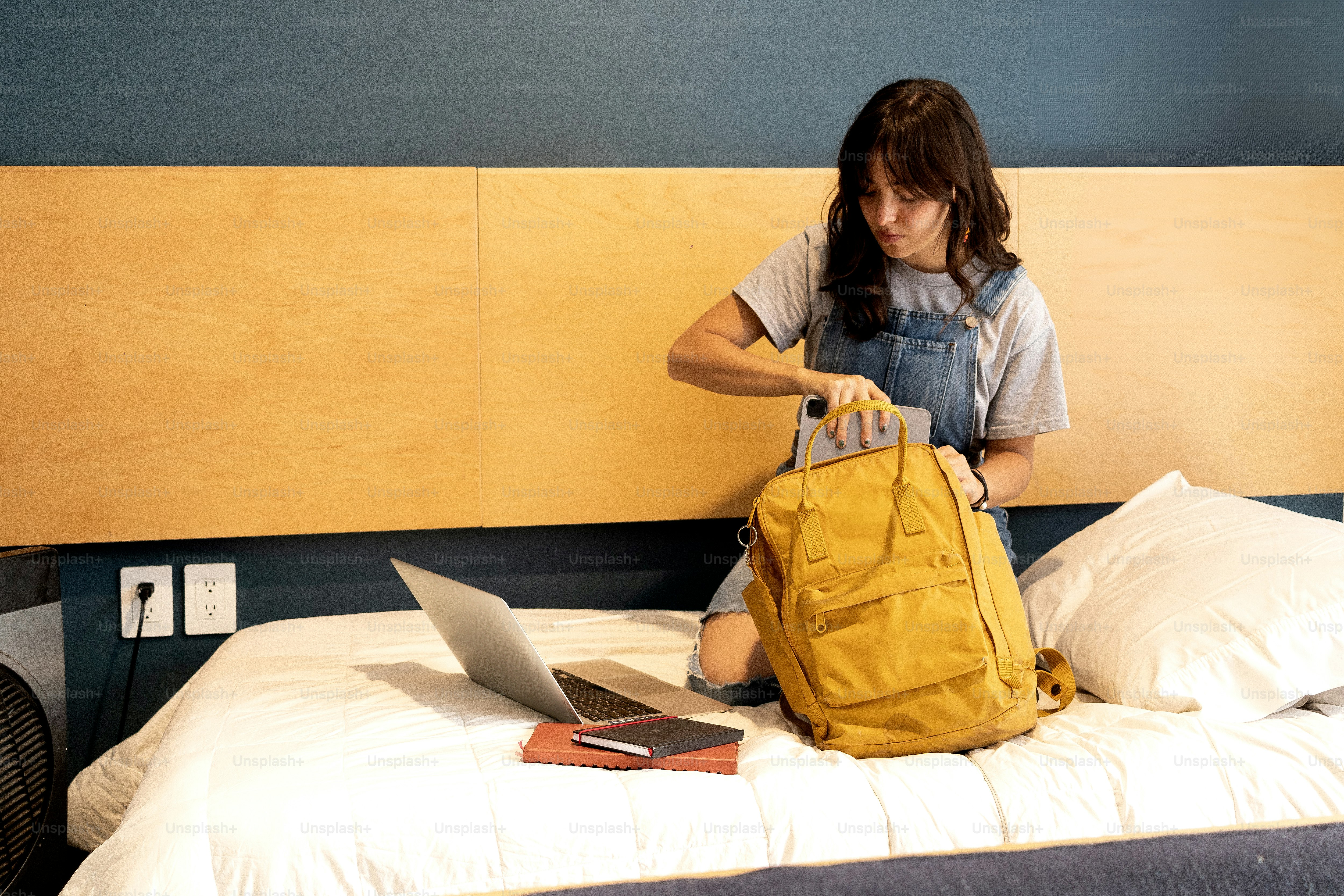 A woman sitting on a bed with a yellow bag