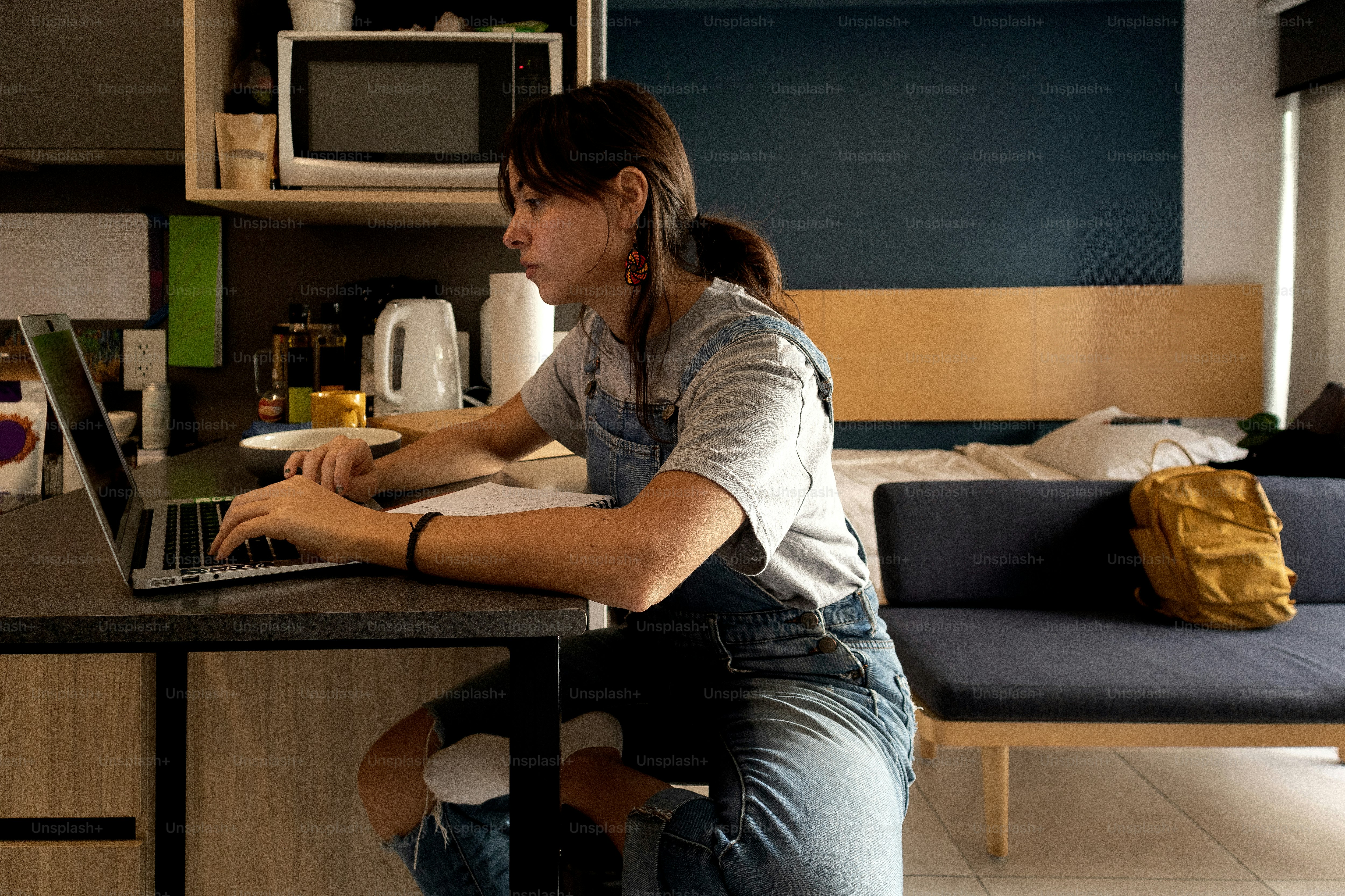 A woman sitting at a kitchen counter using a laptop computer