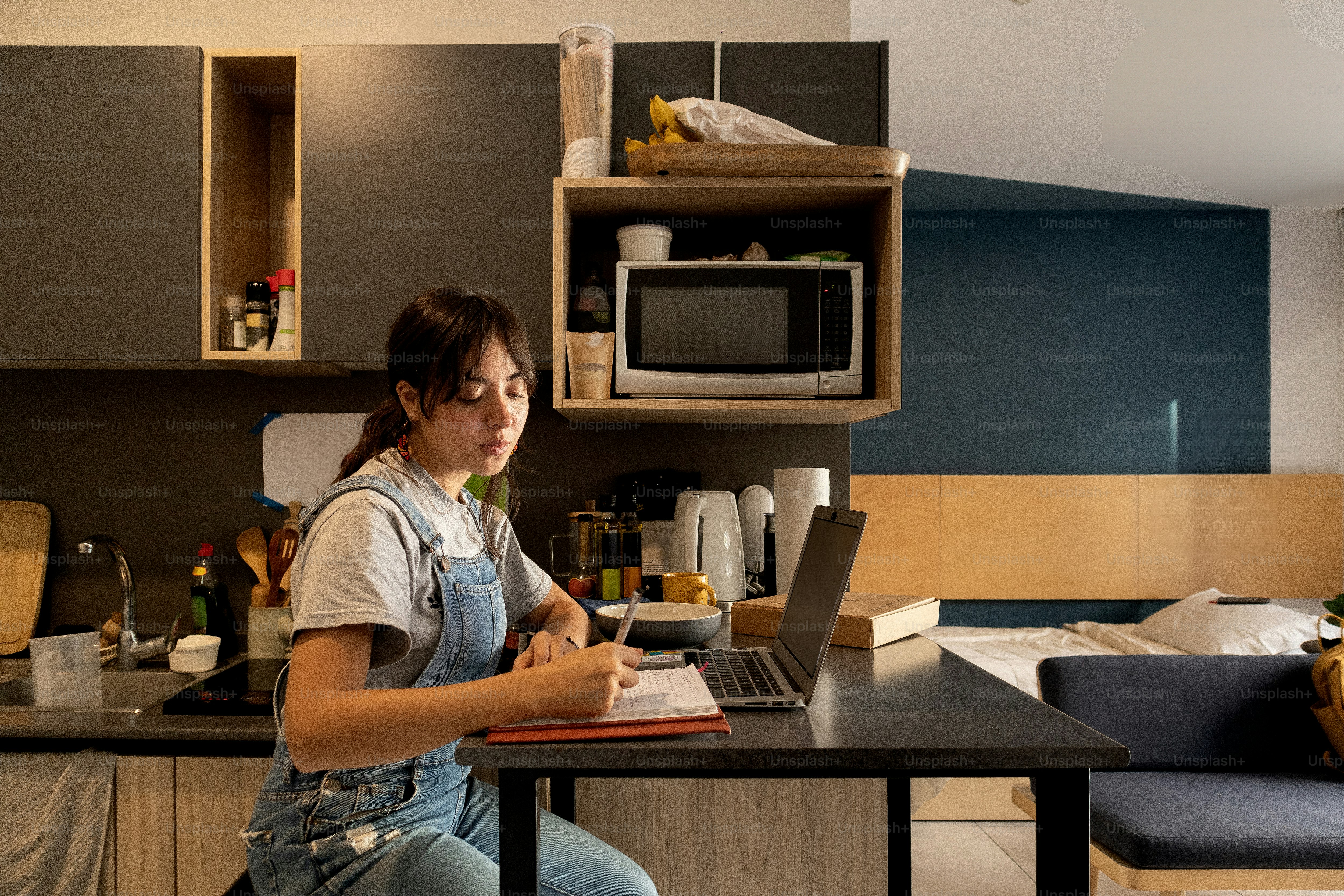 A woman sitting at a kitchen table working on a laptop