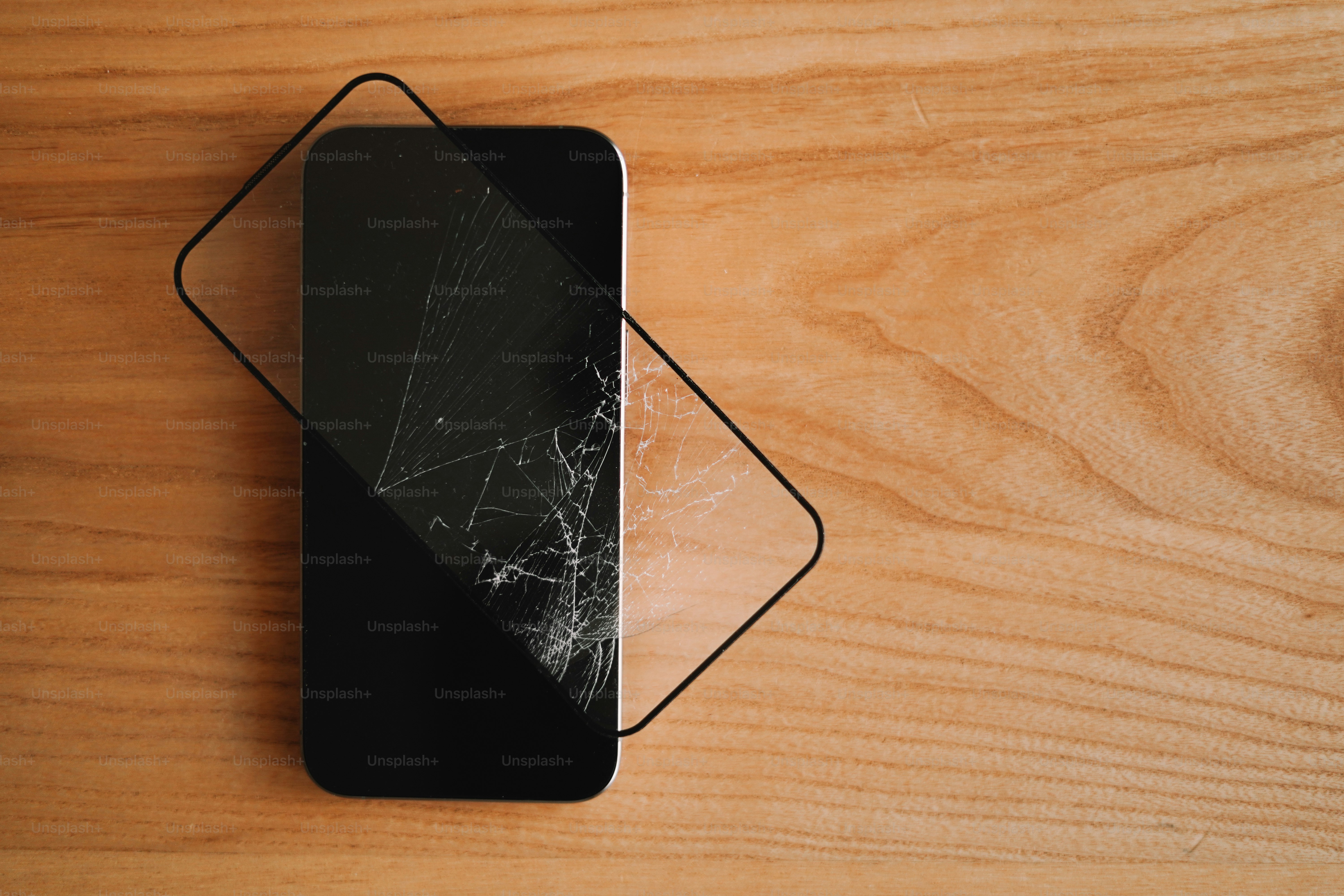 Um telefone celular quebrado sentado em cima de uma mesa de madeira