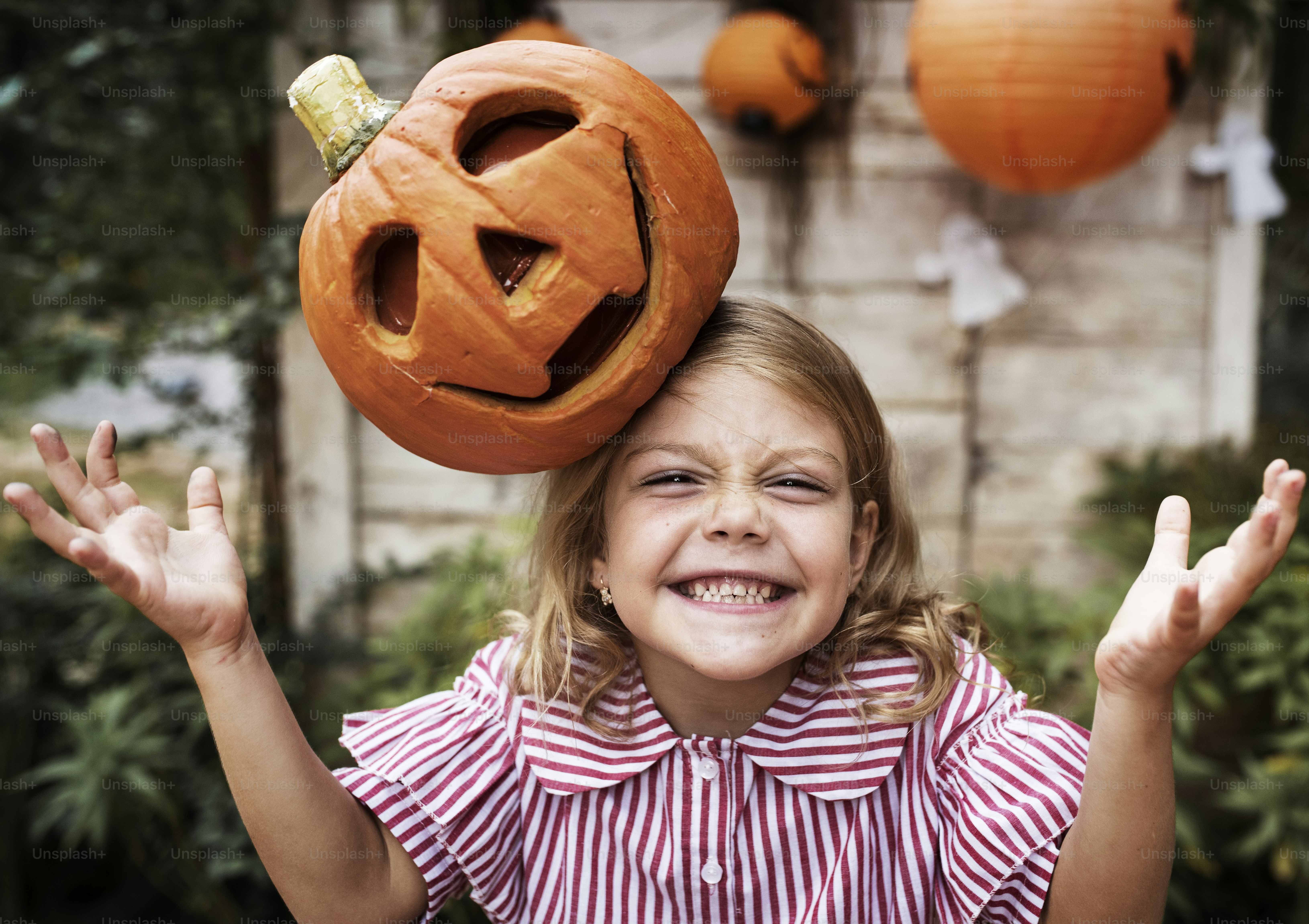 Junges verspieltes Mädchen mit ihrer Halloween-Kürbis-Laterne