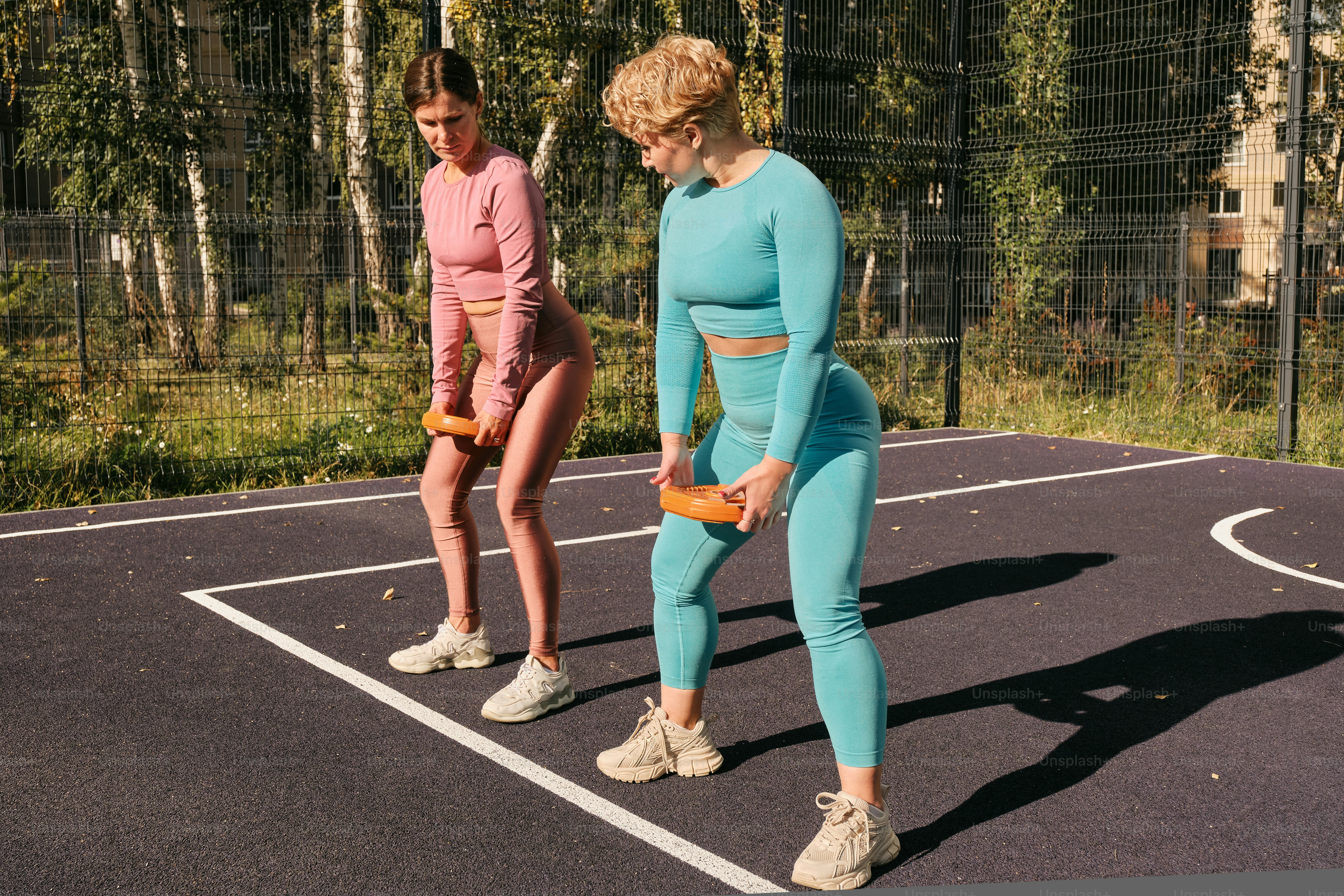 Un par de mujeres de pie encima de una cancha de baloncesto
