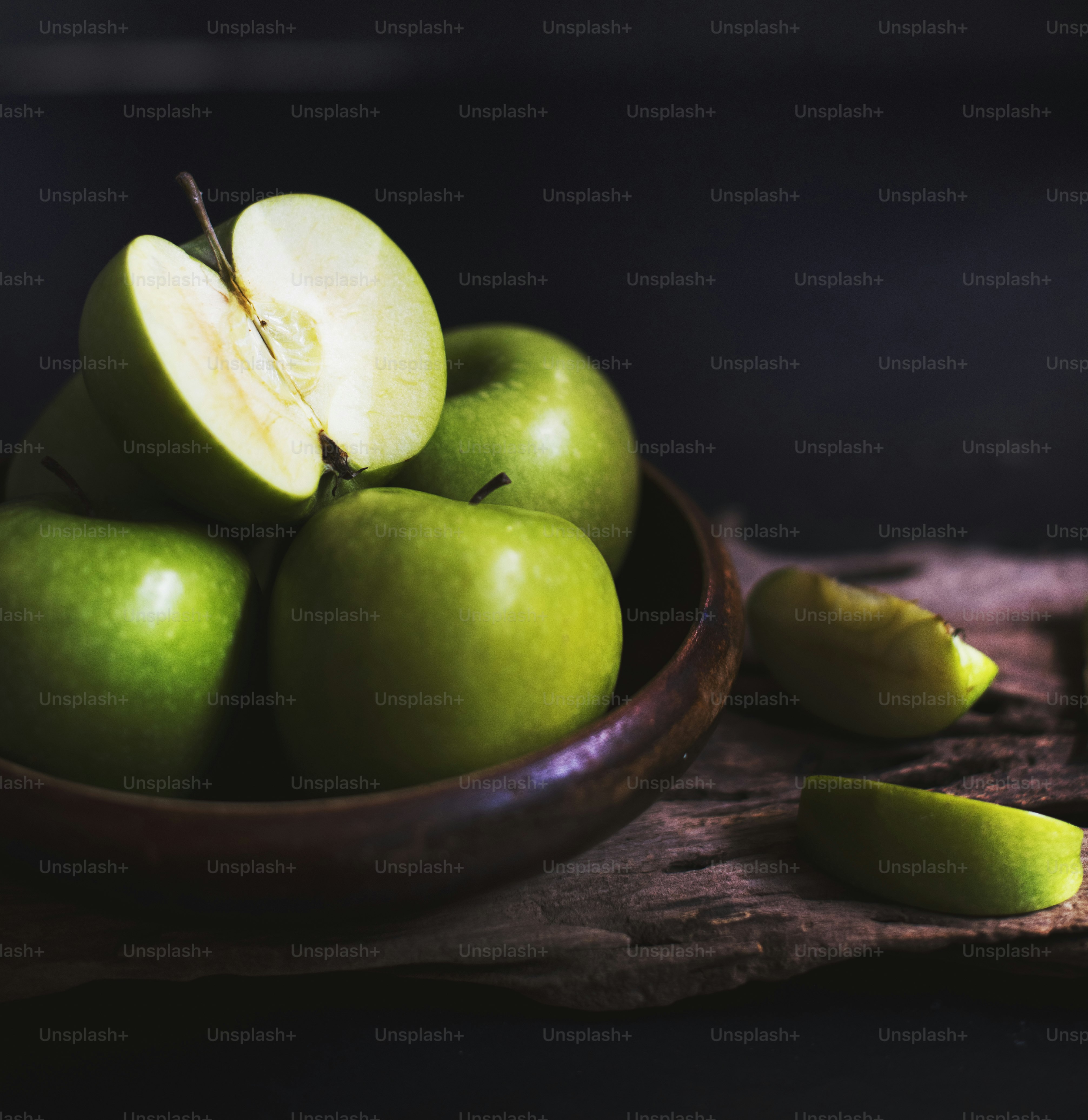 Closeup of fresh cut green apples in wooden bowl with black background