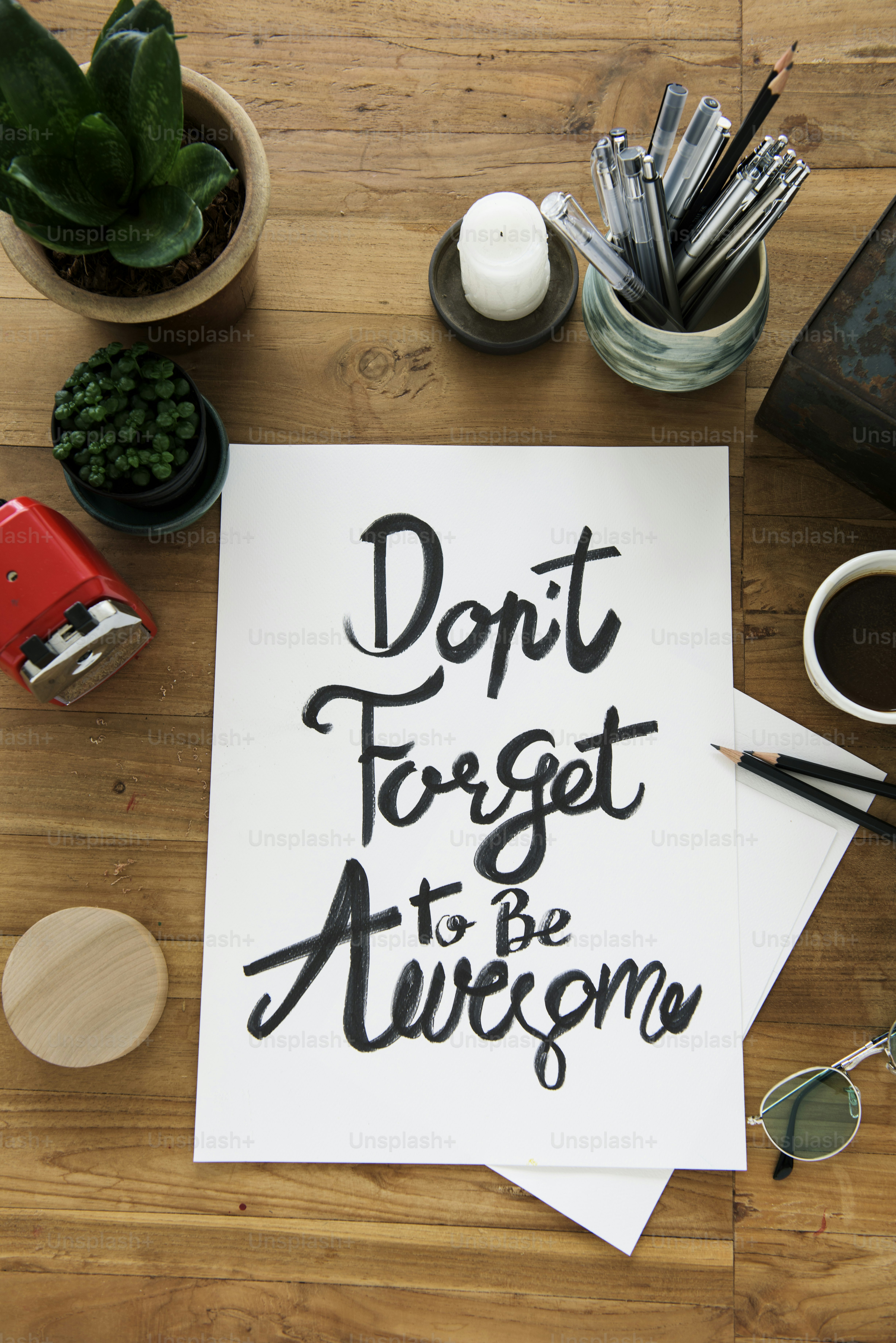 A paper with the handwritten phrase Don't Forget to Be Awesome on a wooden desk
