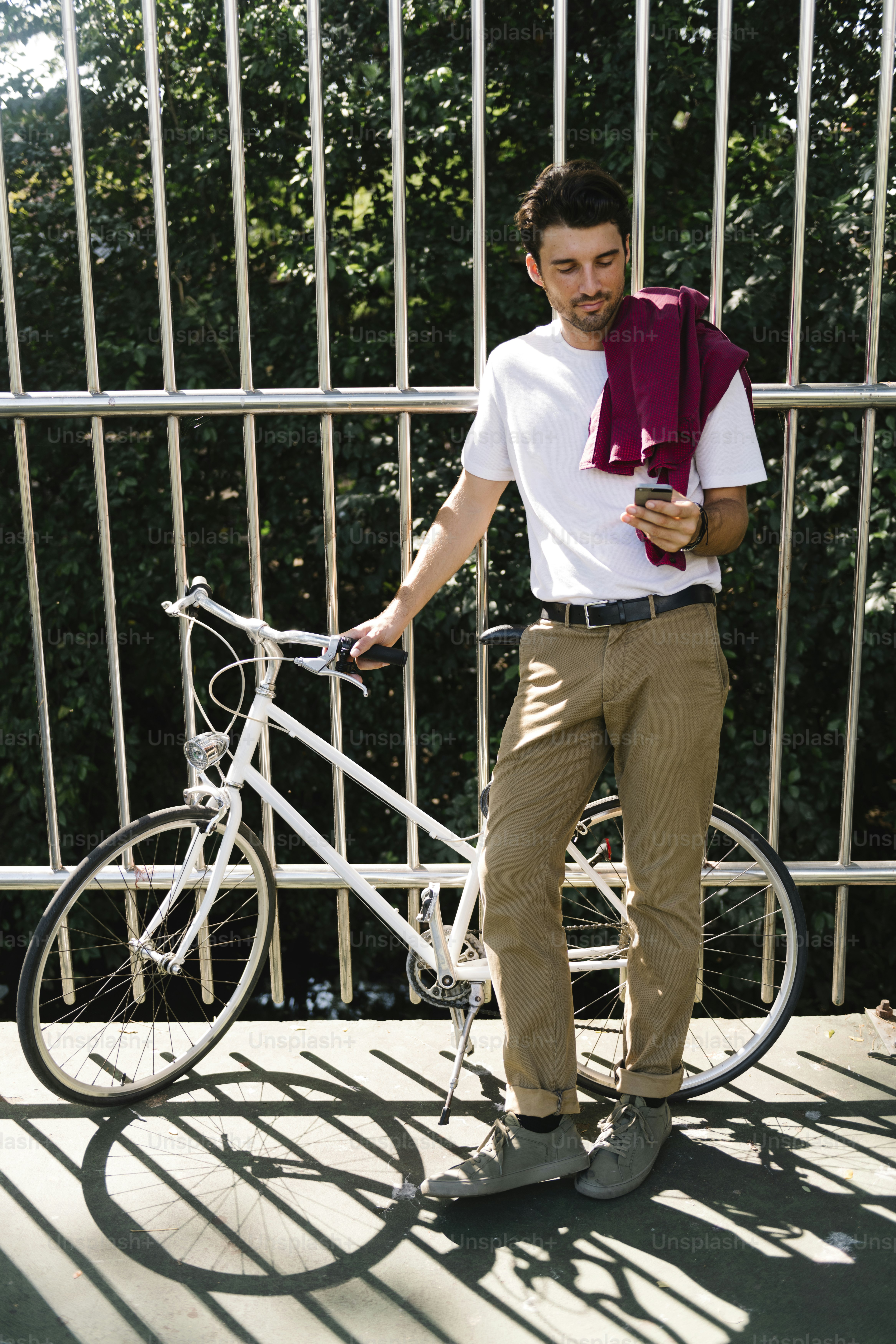 Caucasian man standing by bicycle and using moblie phone