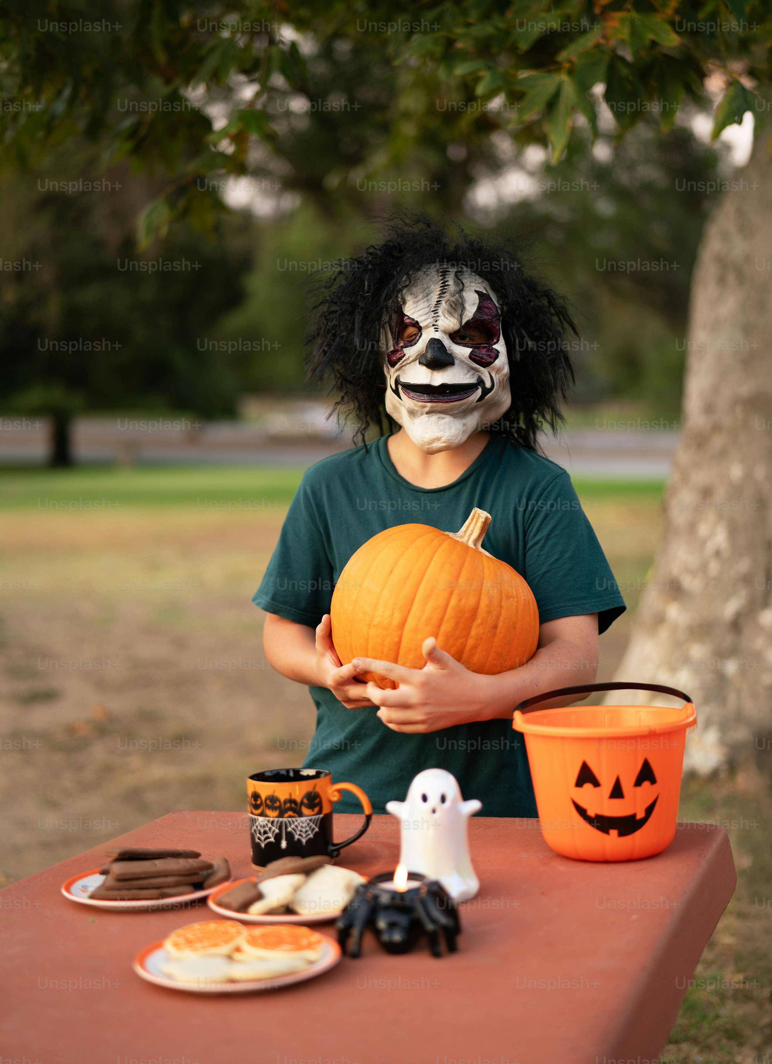 A person with a scary face holding a pumpkin