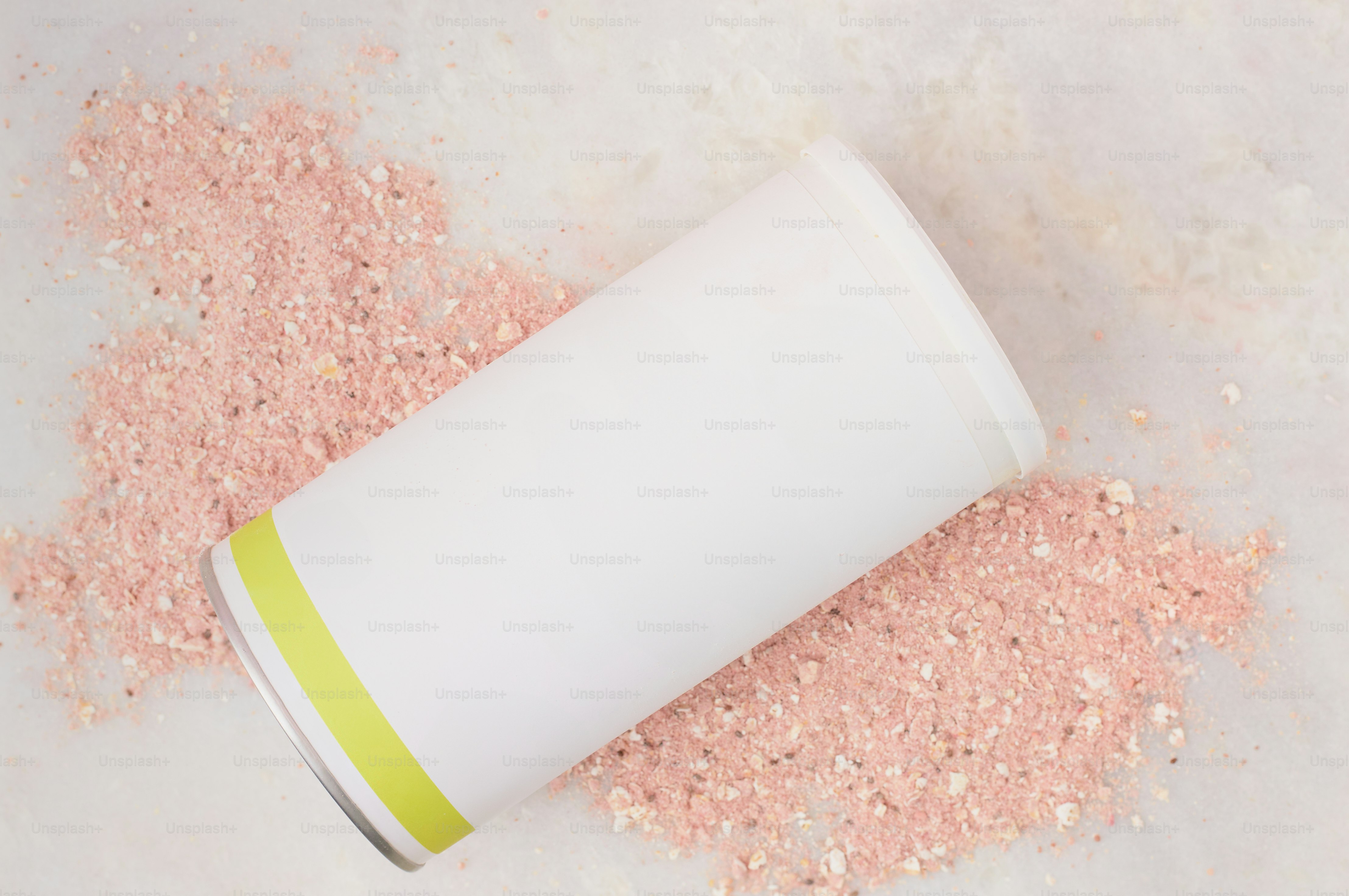A white container filled with pink sand next to a white cup