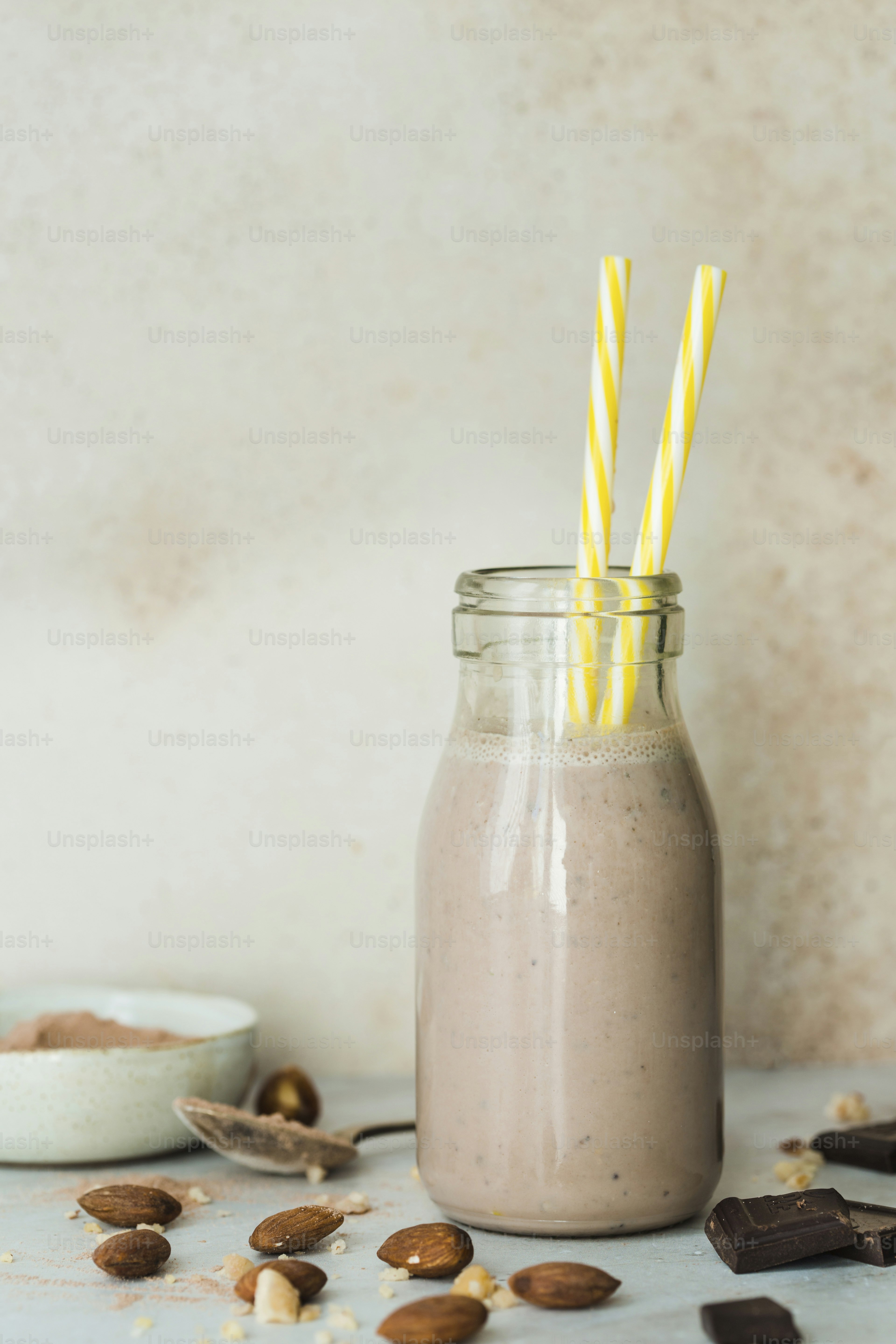 A glass jar filled with a smoothie next to a bowl of nuts