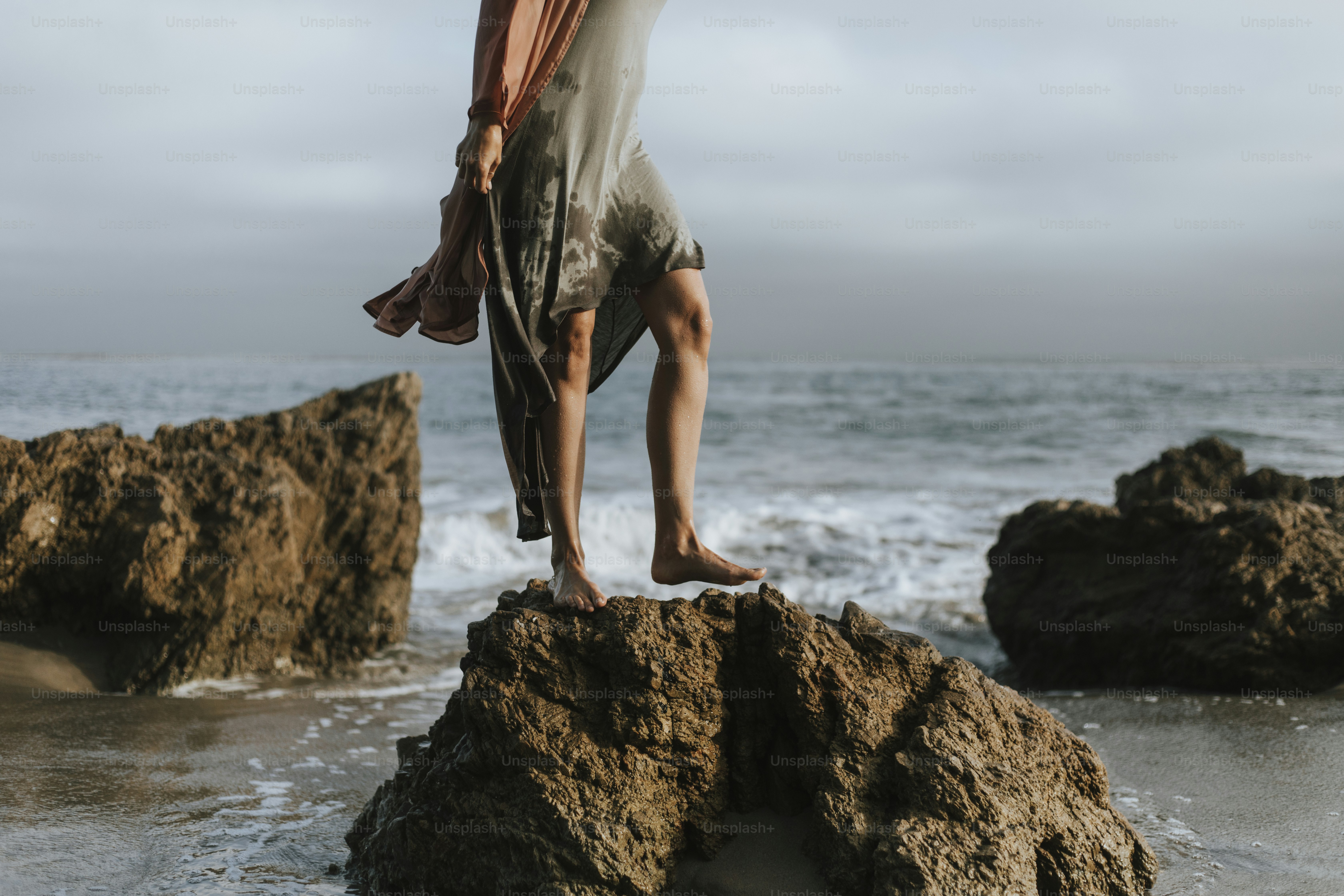 Woman's legs standing on a rock at the beach
