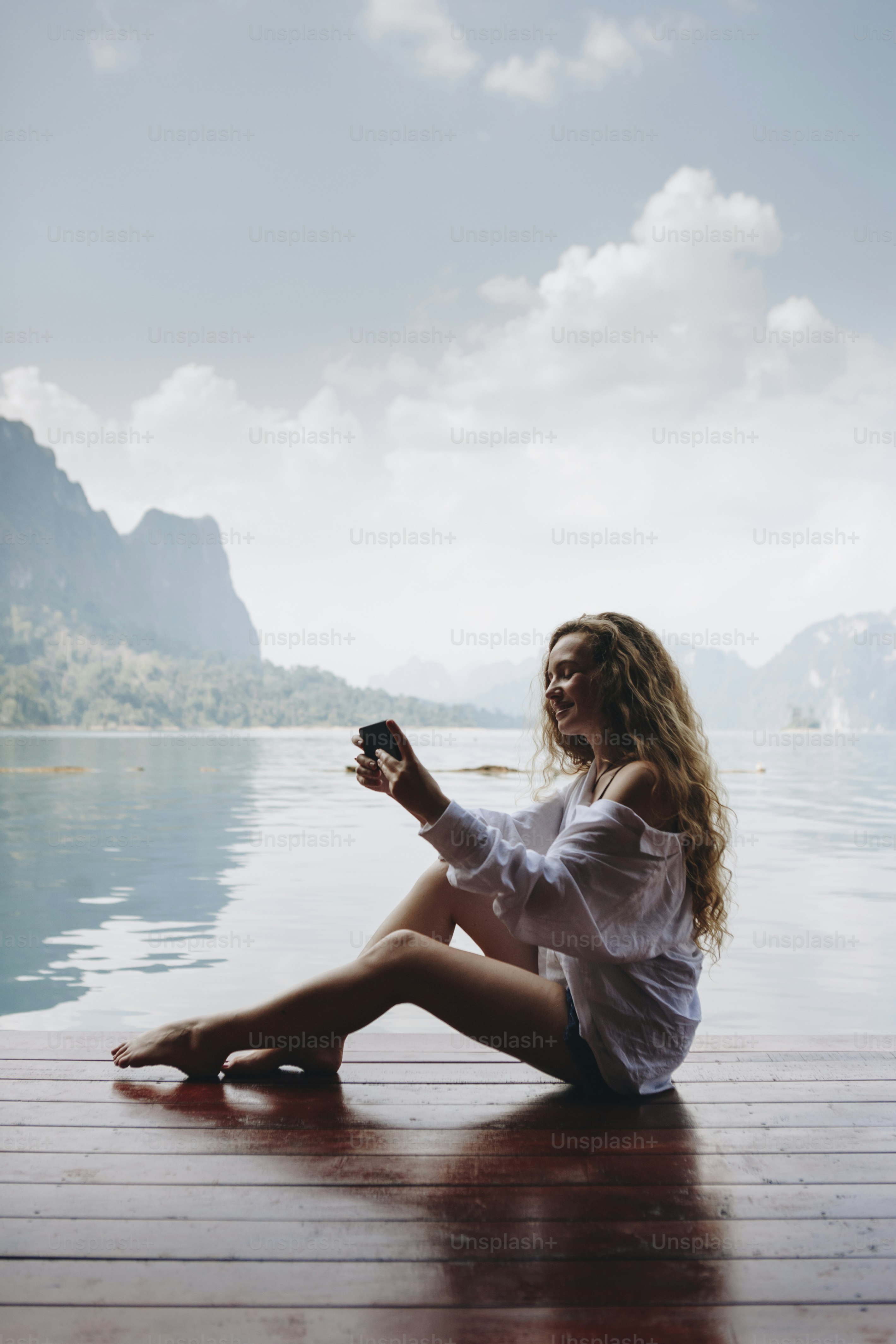 Woman using her phone by a lake