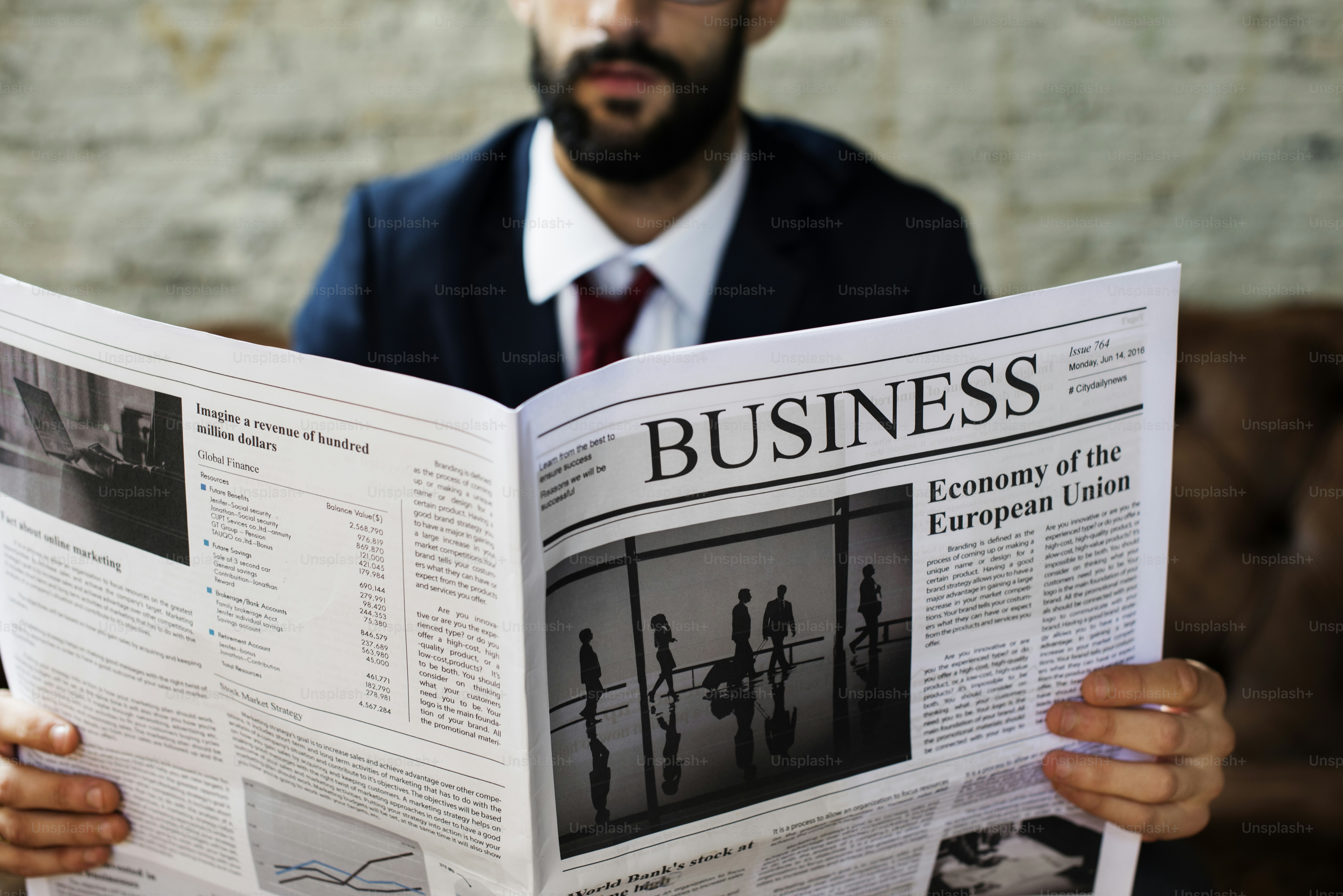 A person in a suit reading a business newspaper with financial headlines