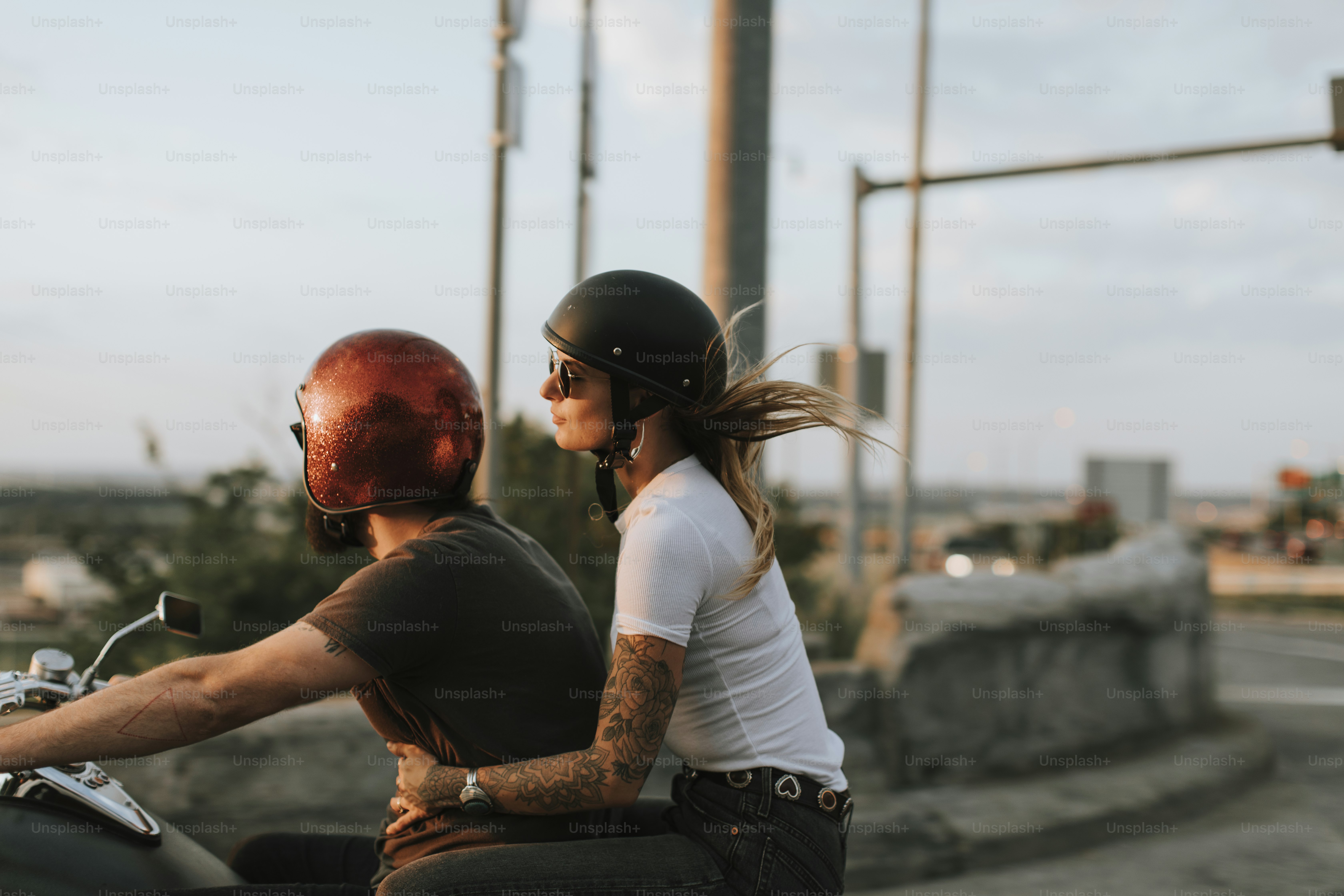 Coppia di motociclisti che cavalca lungo la strada al tramonto