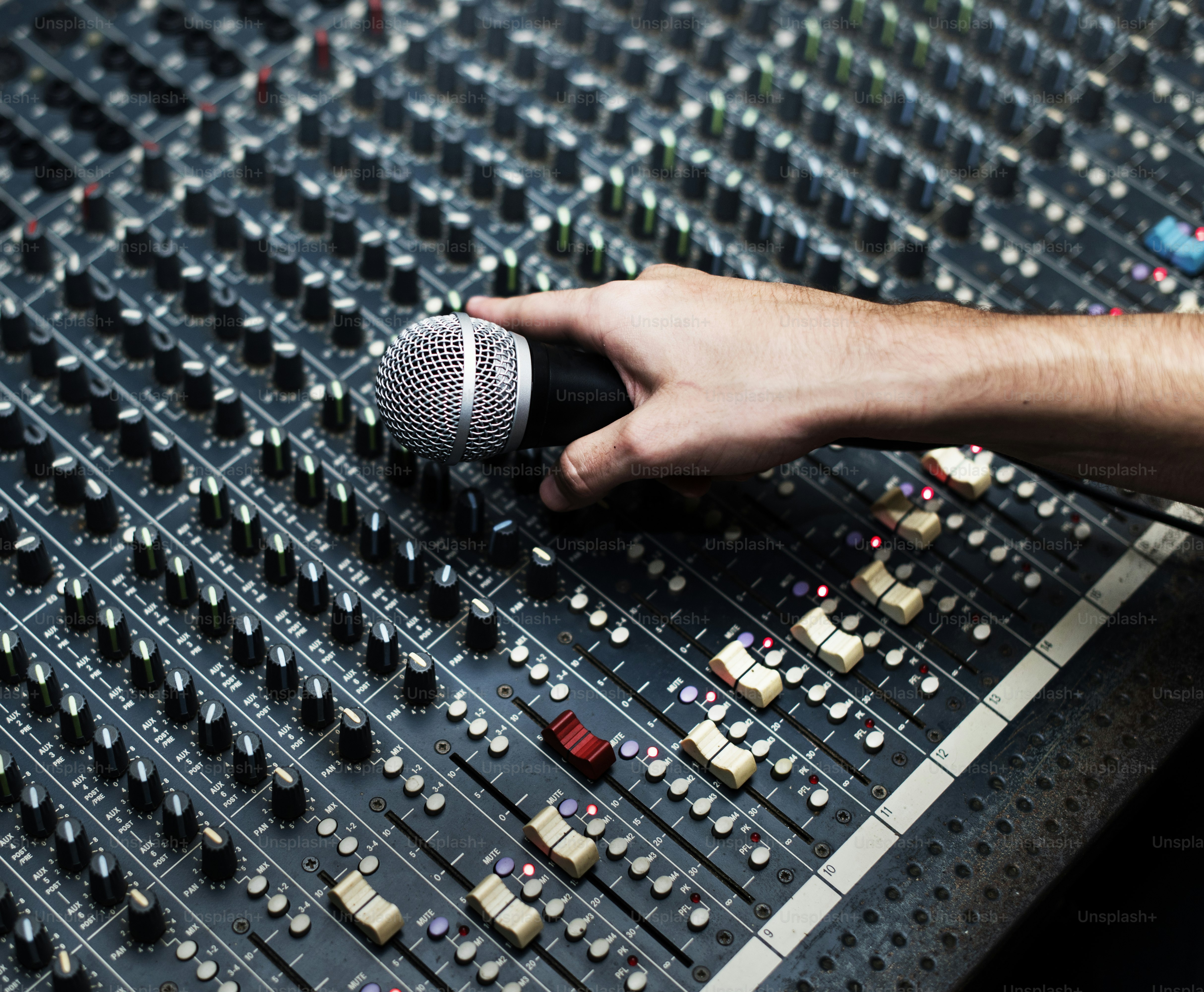 Mano con micrófono en un mezclador de sonido