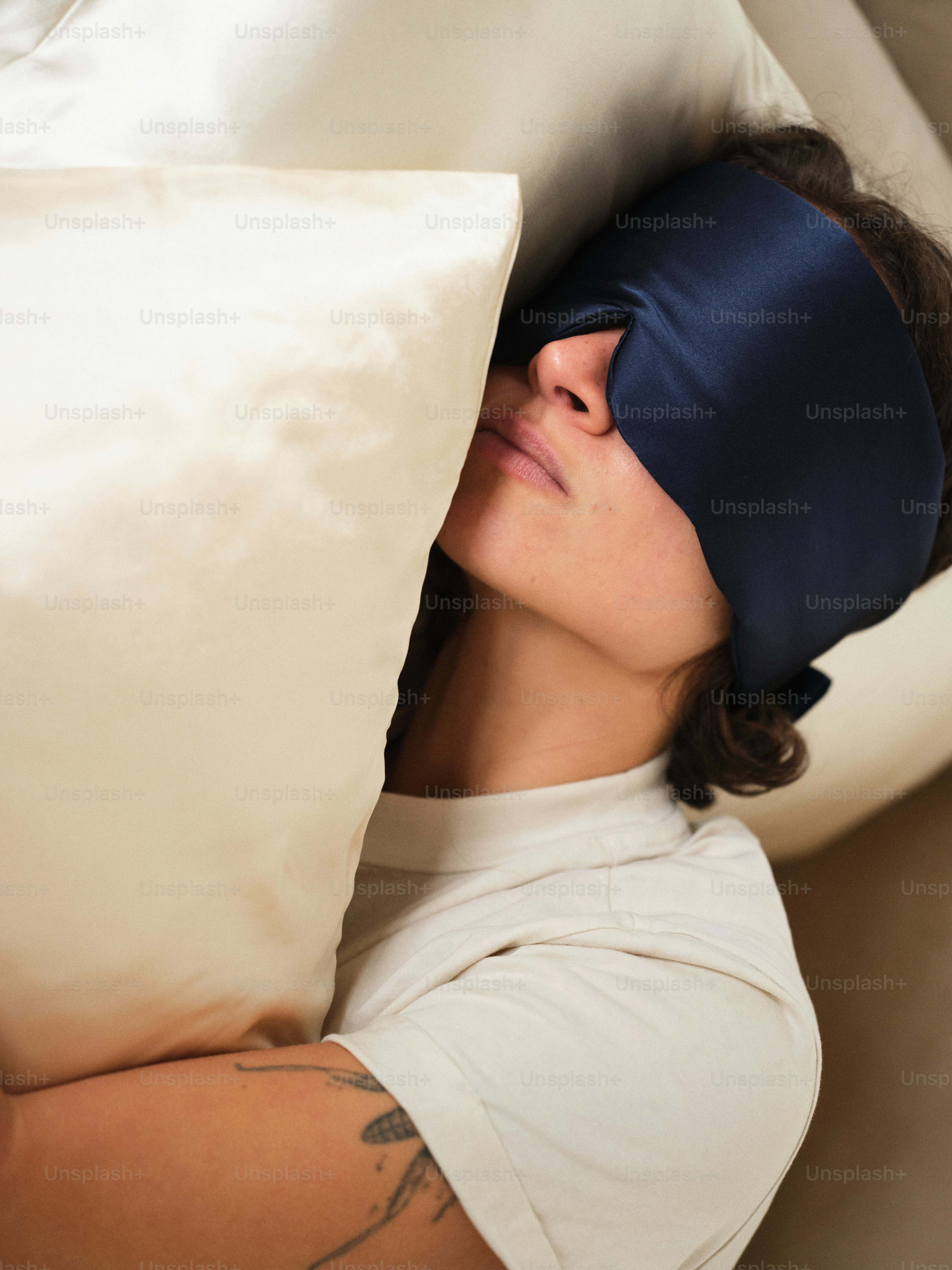 A woman laying in bed with a blindfold on her face