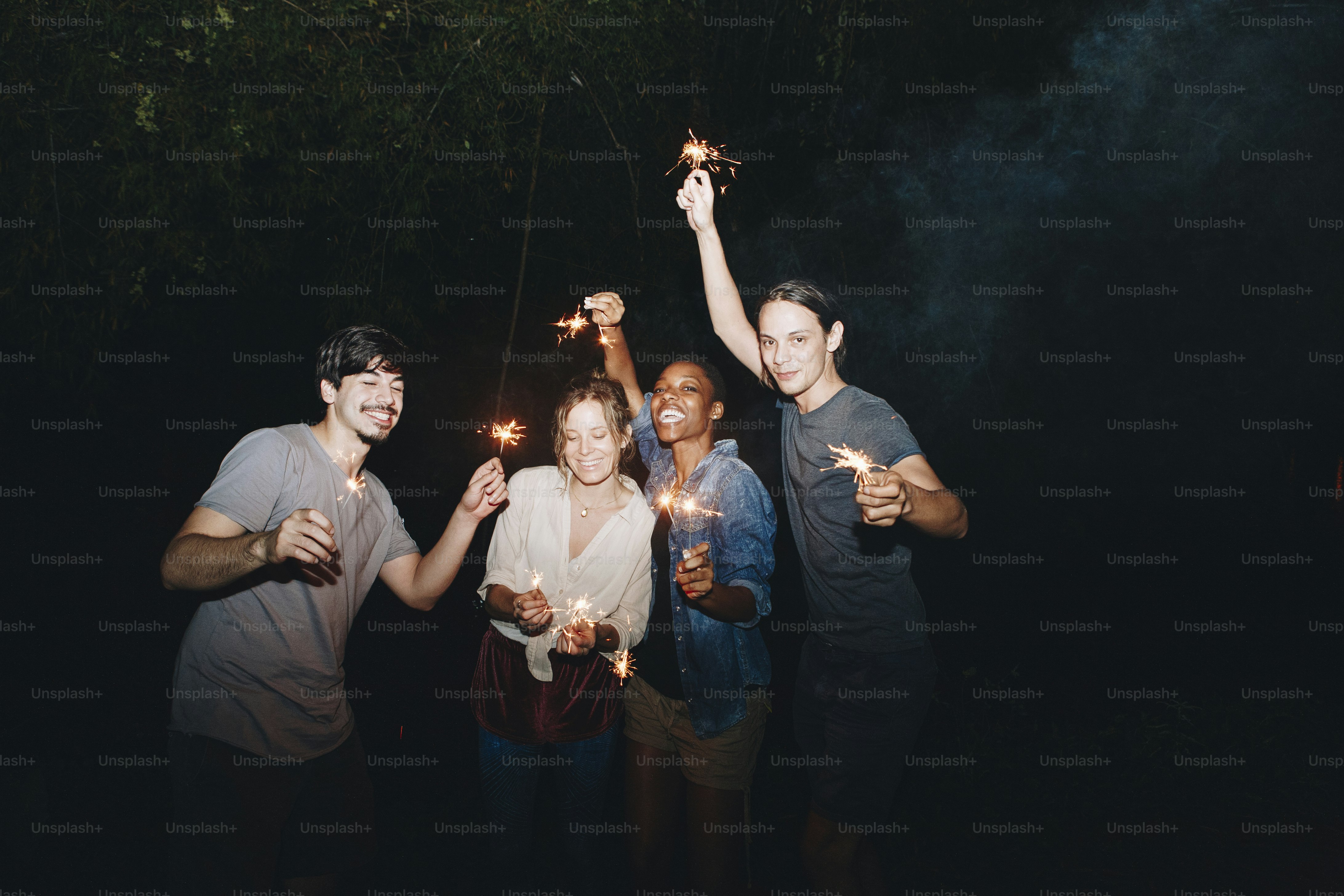 Mixed race friends playing with sparklers celebration and festive party concept
