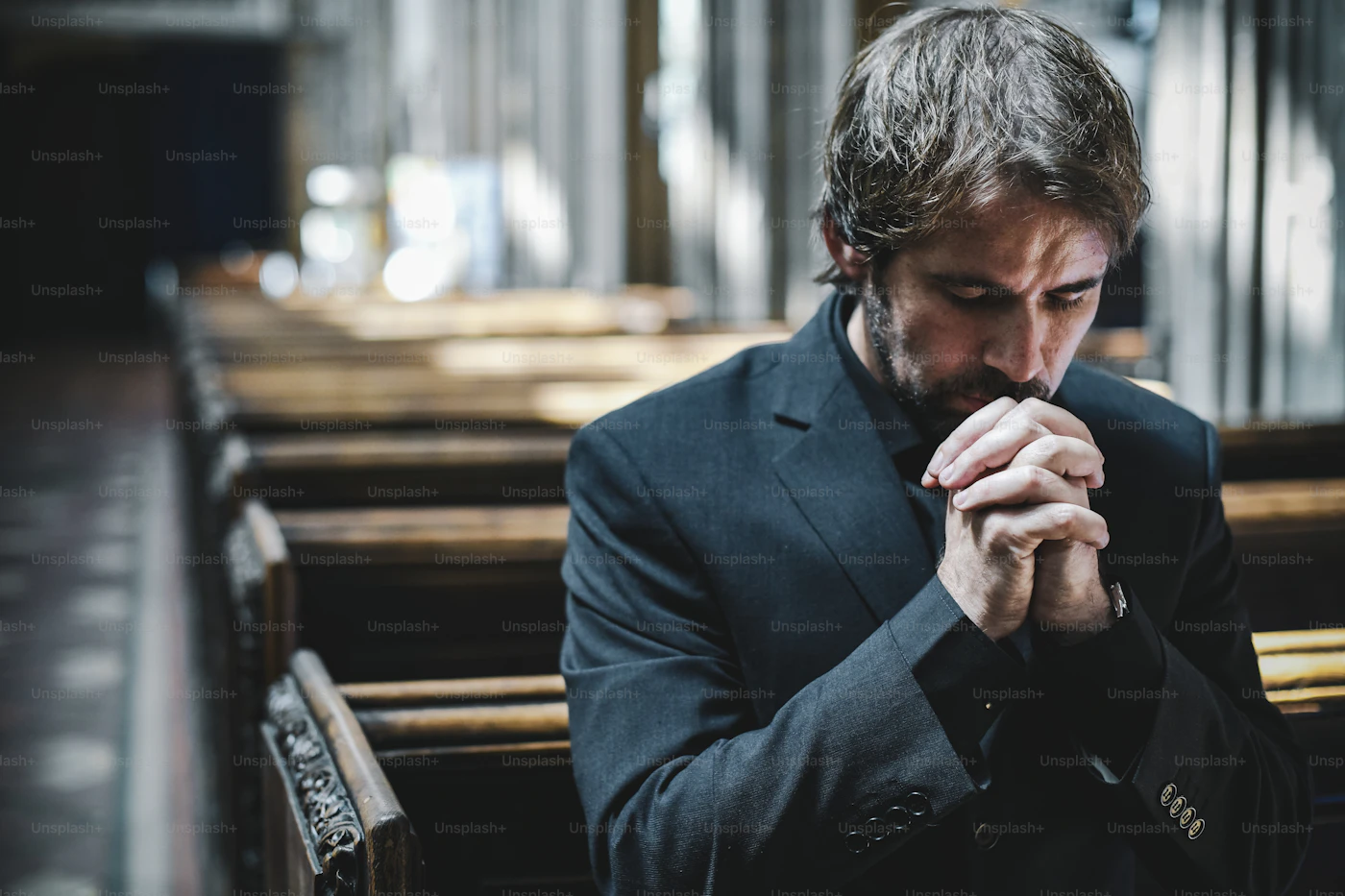 A man praying alone among empty church pews