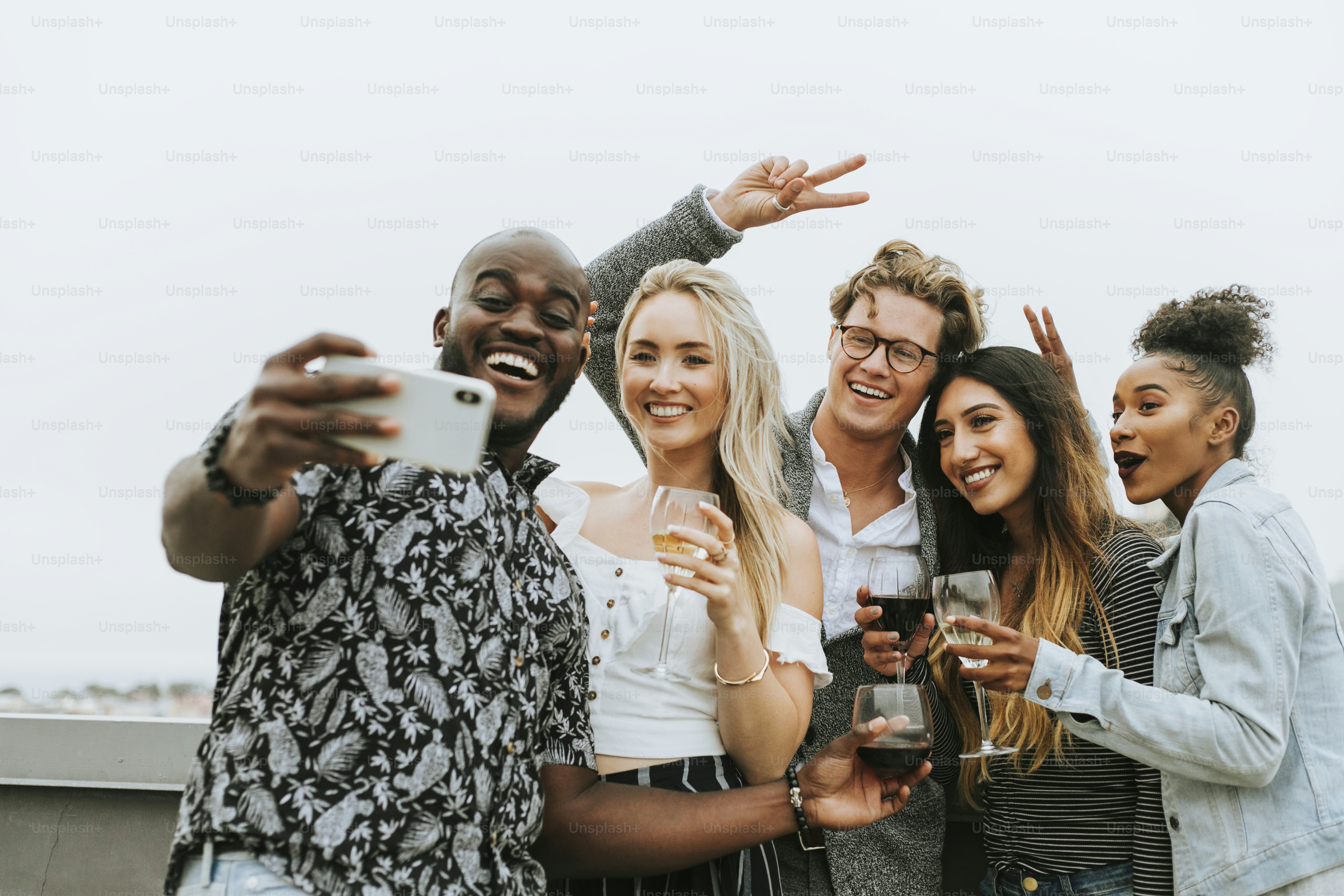 Diverse group of friends taking a selfie at a rooftop party photo ...