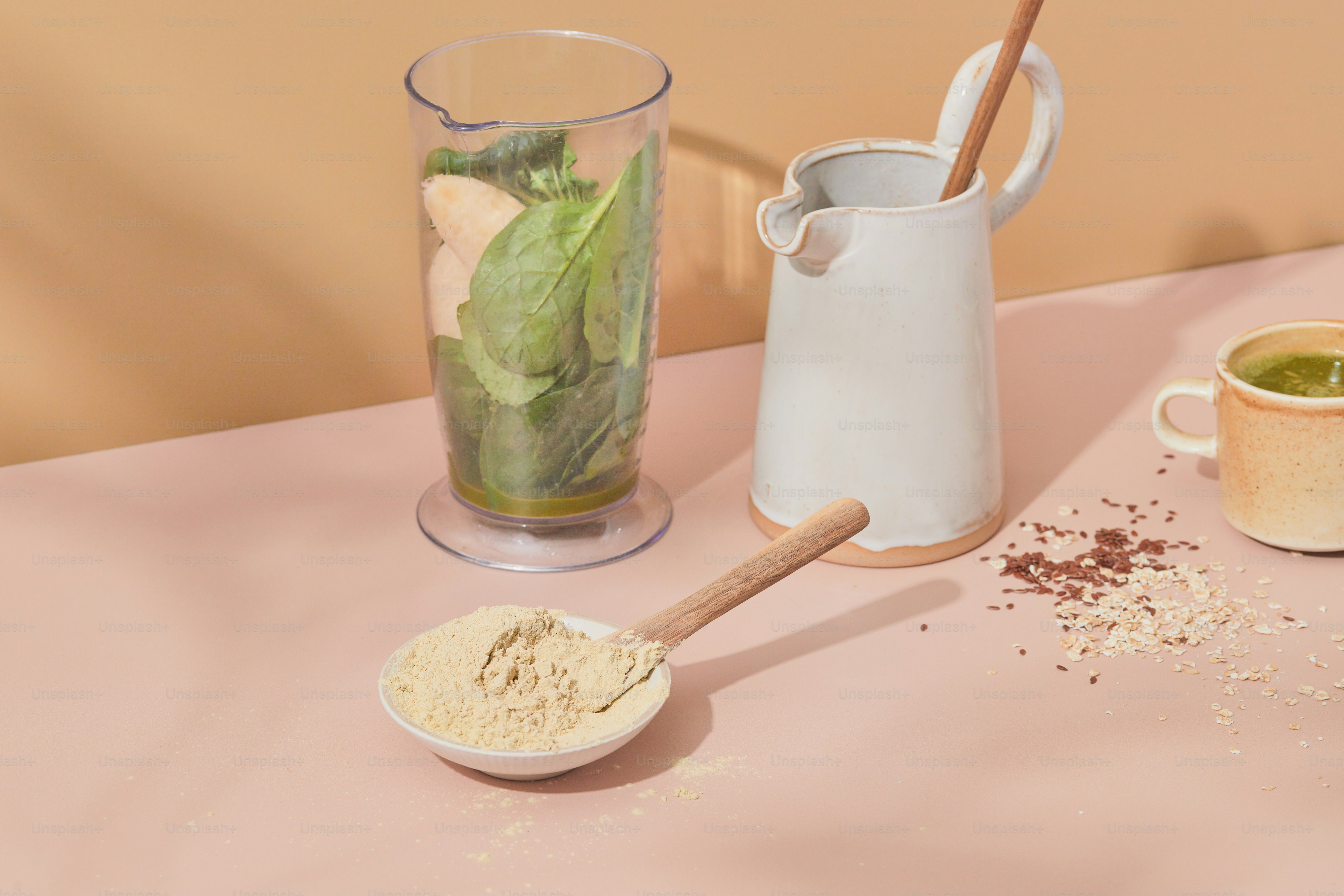 A table with a pitcher of green tea, a cup of tea and a spoon