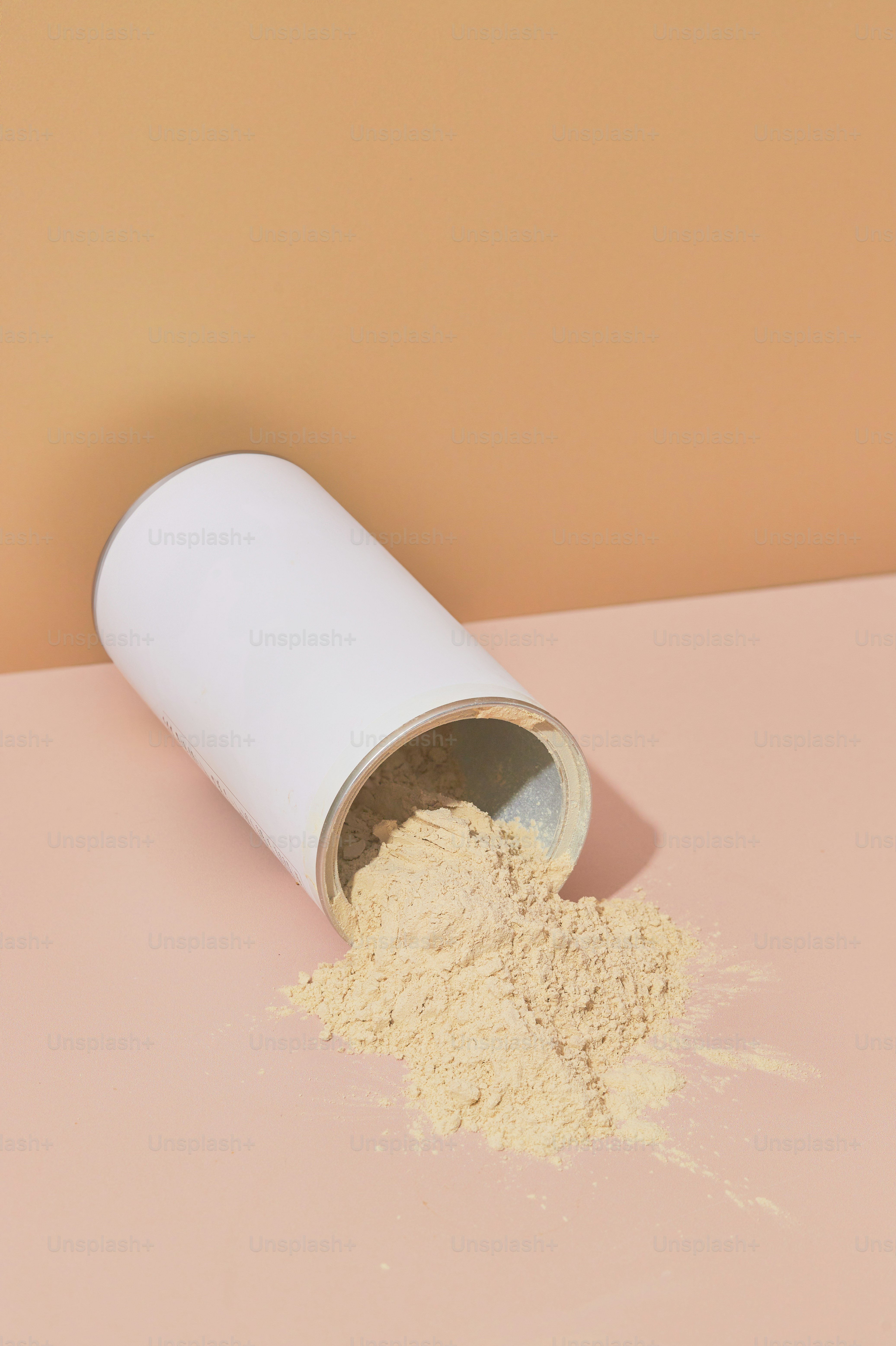 A white container filled with white powder on top of a pink table