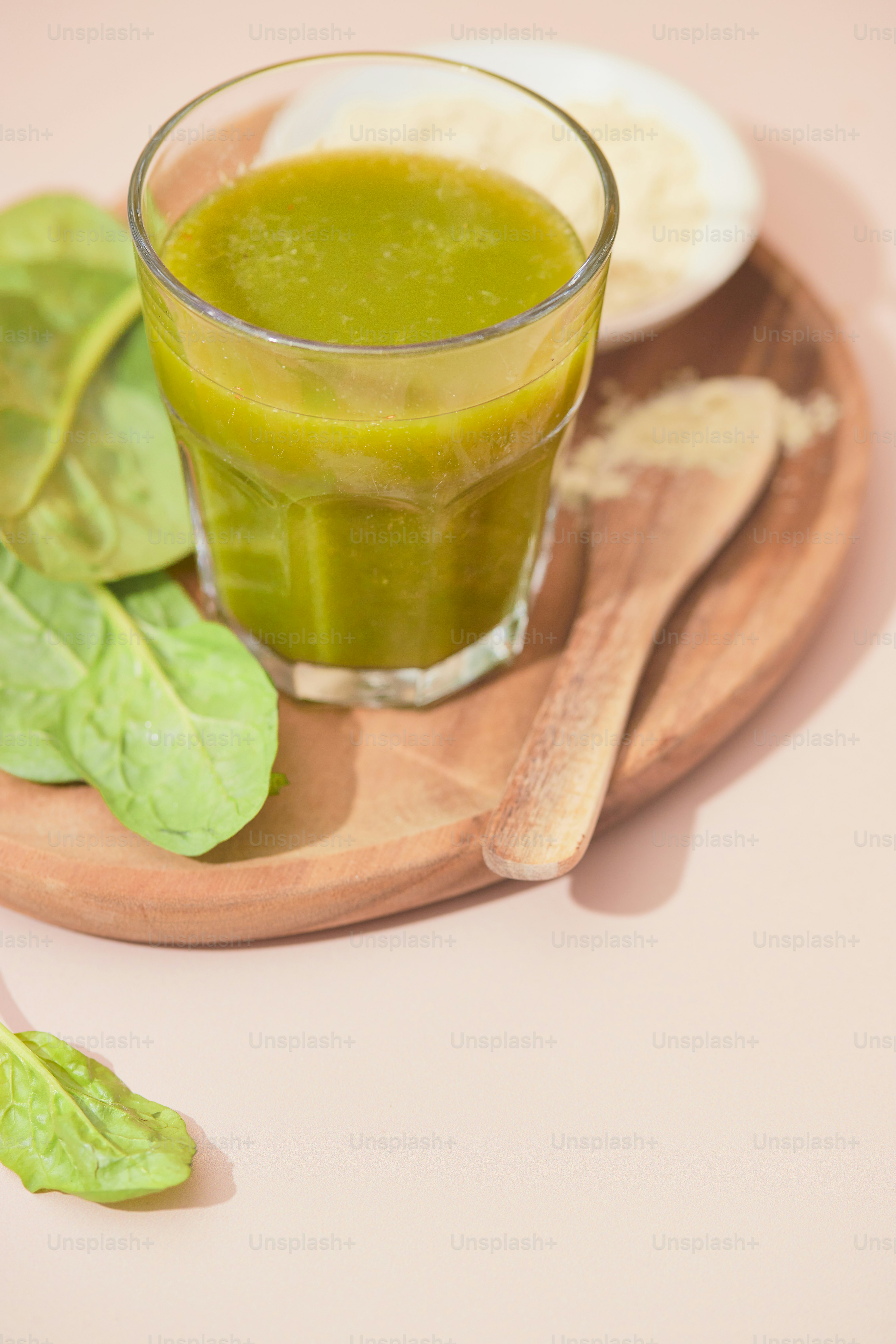 A glass of green juice on a wooden plate