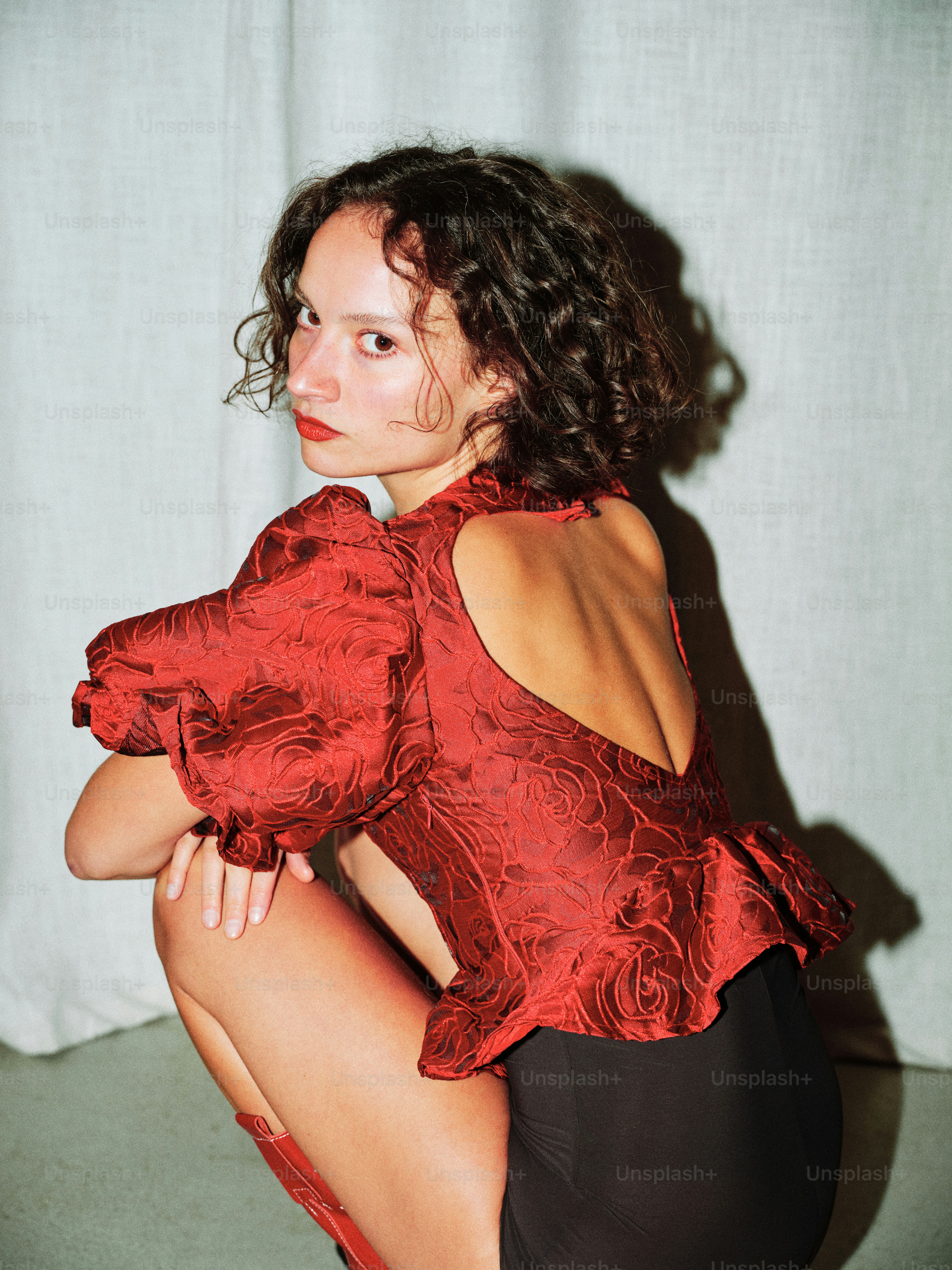 A woman in a red top sitting on the floor