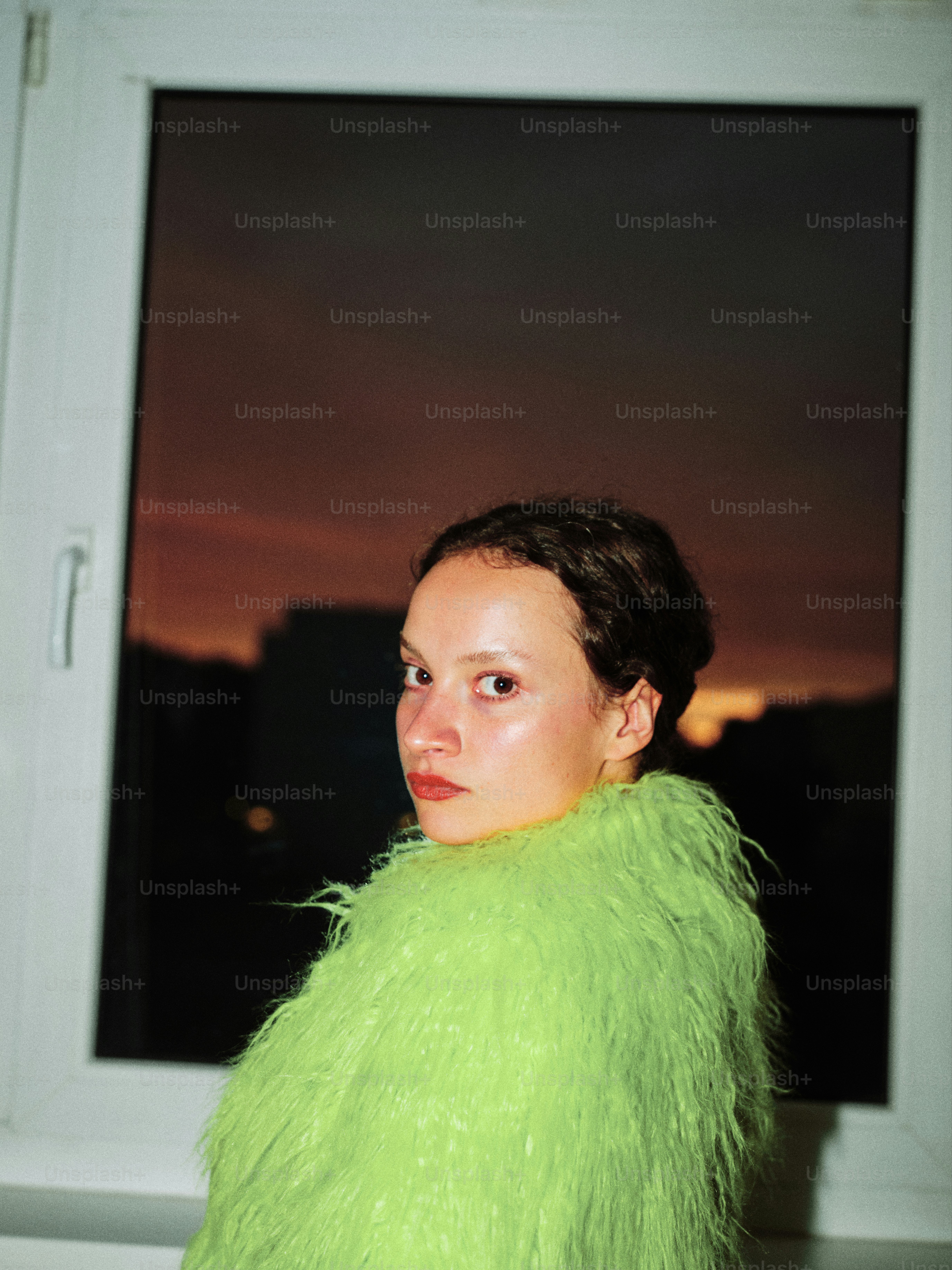 A woman in a green coat looking out a window