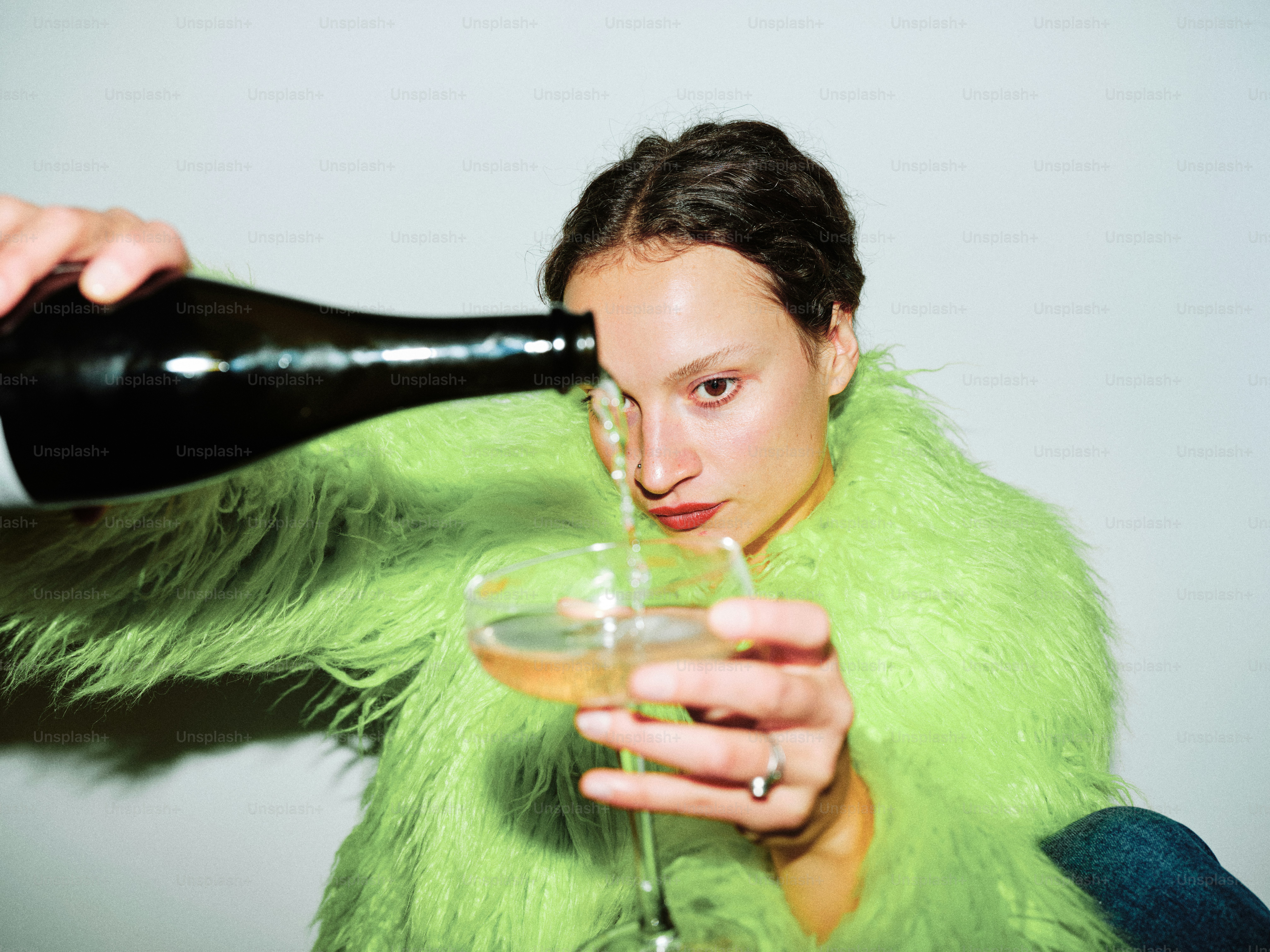 Une femme en manteau de fourrure vert tenant un verre de vin