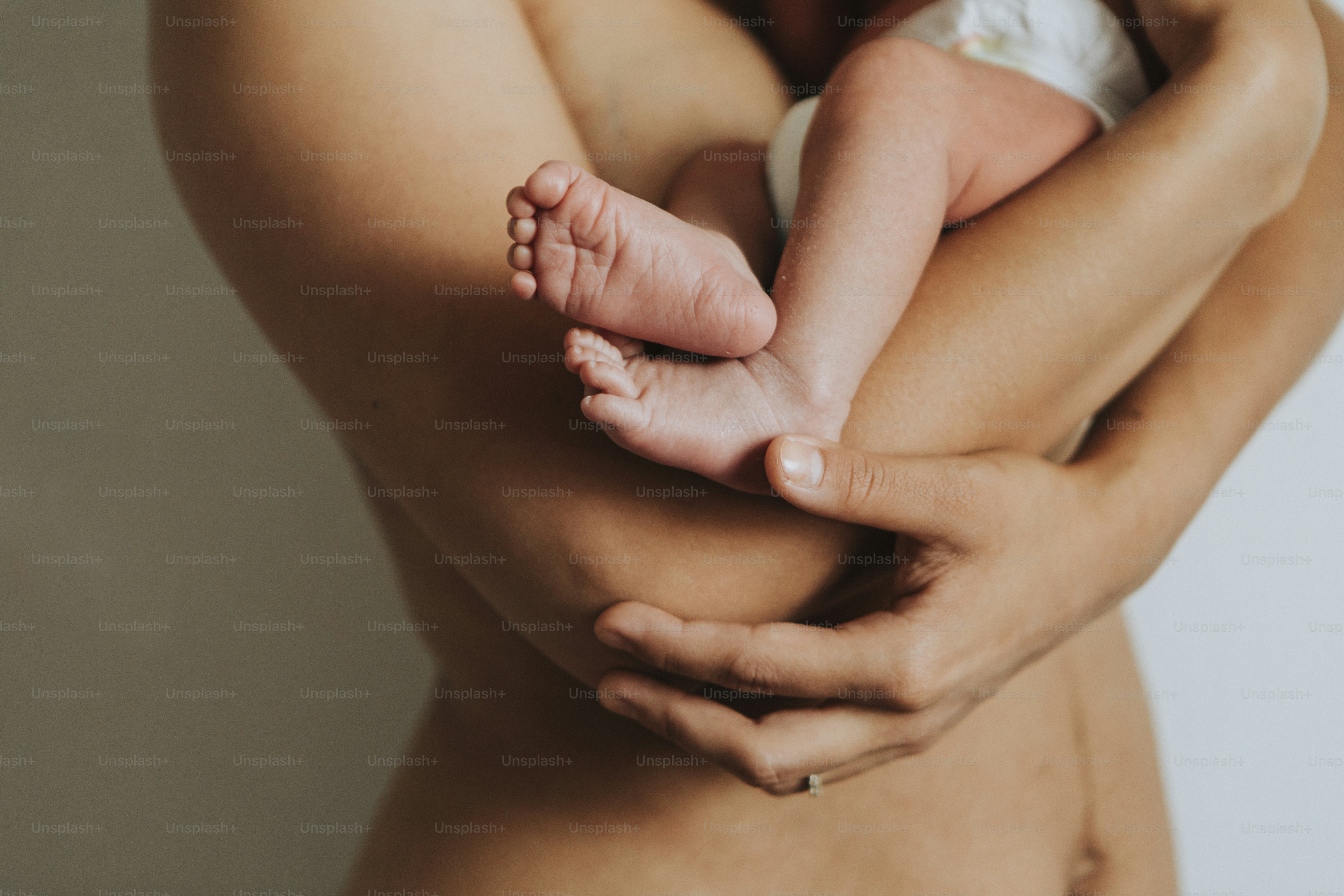 Naked mother holding her infant baby