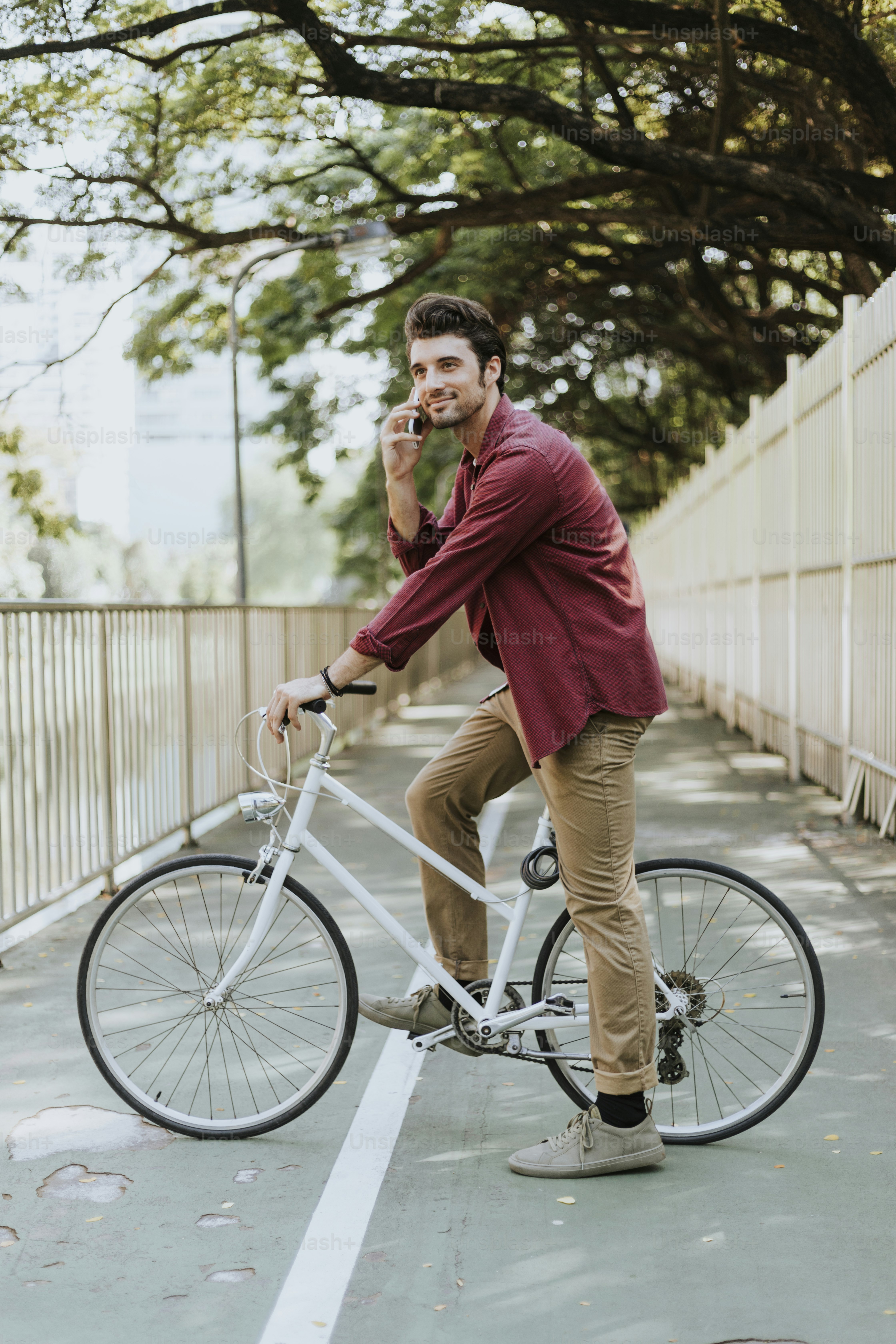 Young caucasian man circling at park and using mobile phone