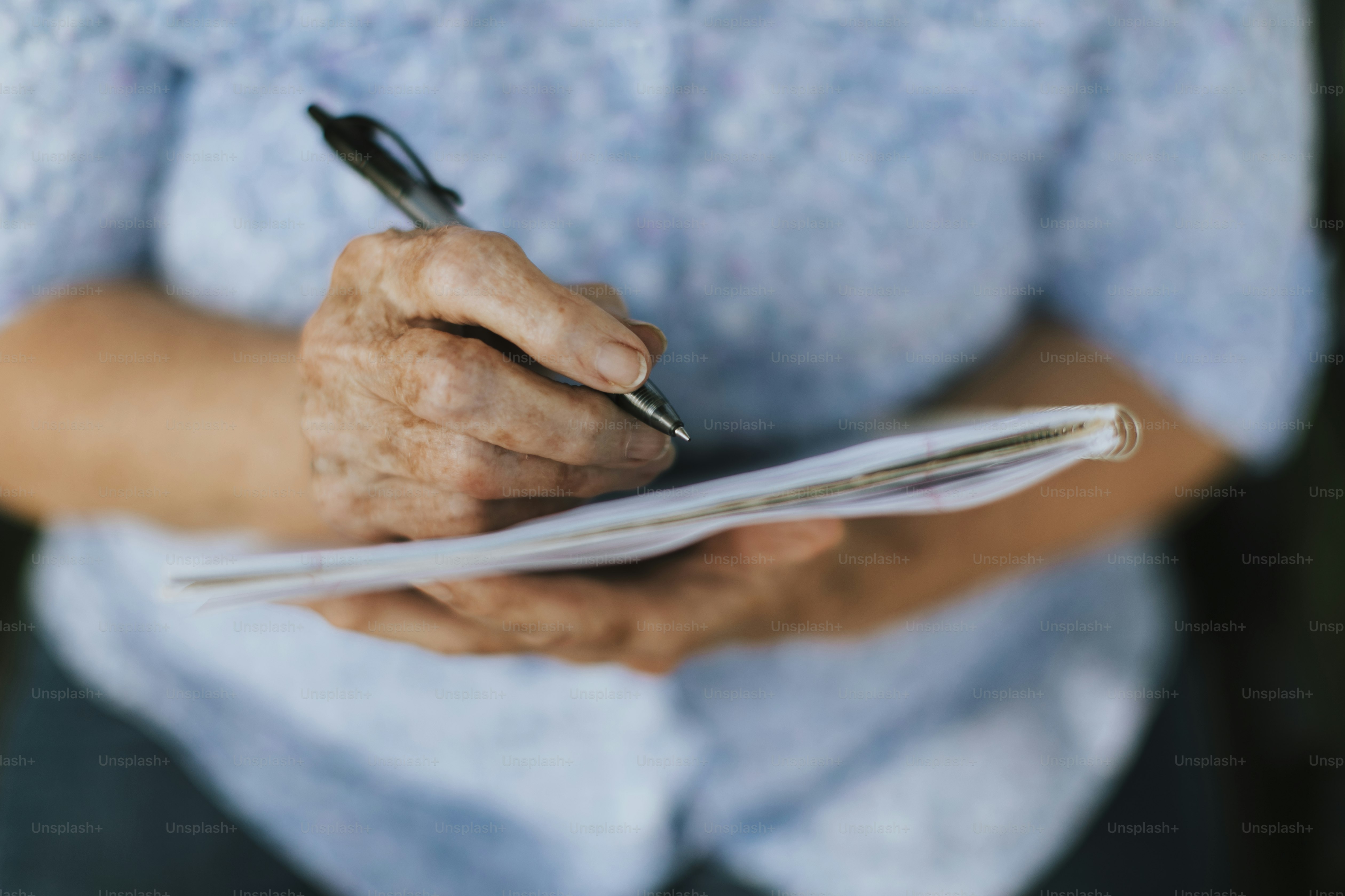 Senior woman writing down her memories into a notebook